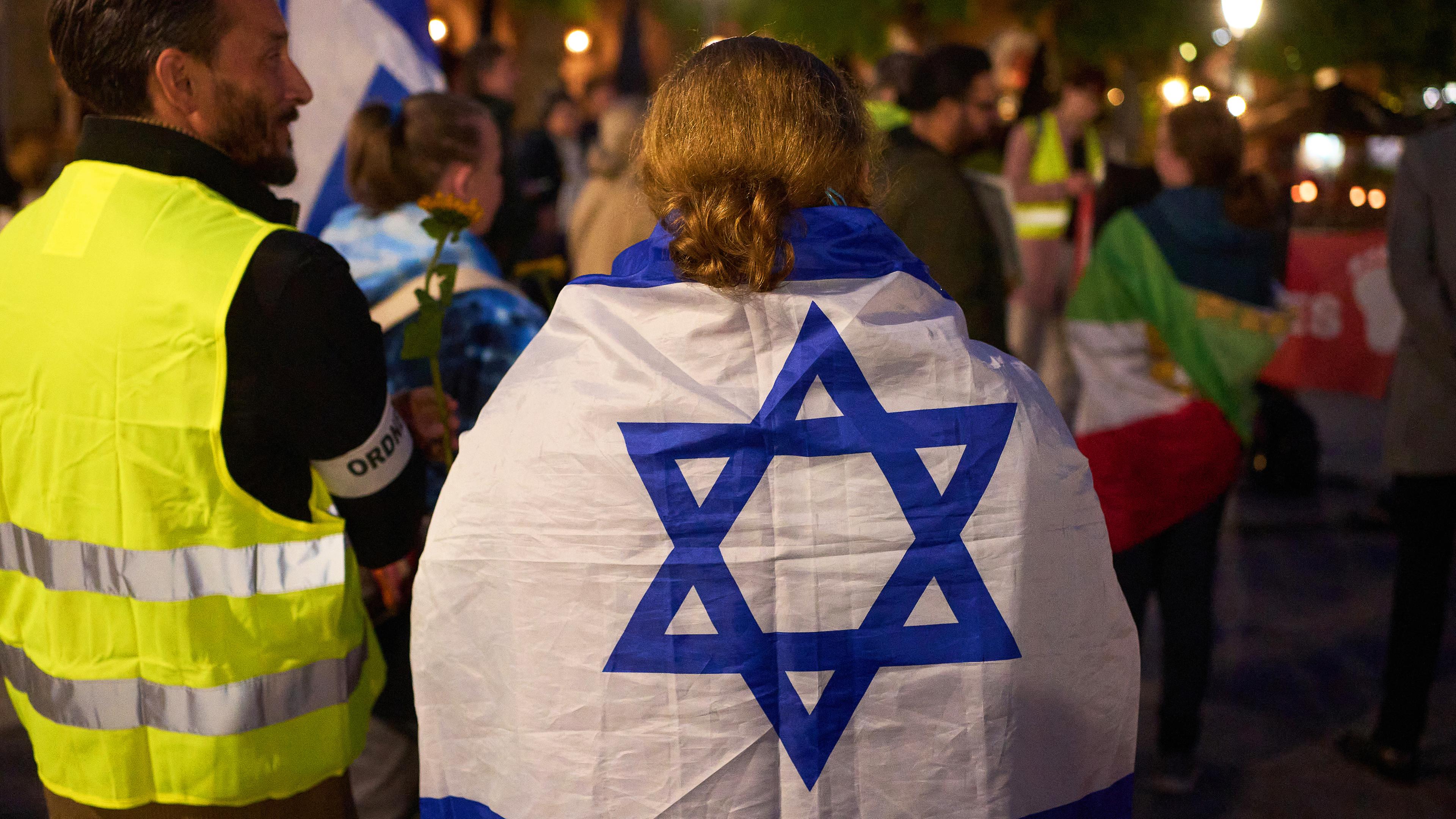 Rheinland-Pfalz, Koblenz: Eine Teilnehmerin einer Demonstration gegen Antisemitismus trägt am Jahrestag des Hamas-Angriffes auf Israel eine israelische Flagge.