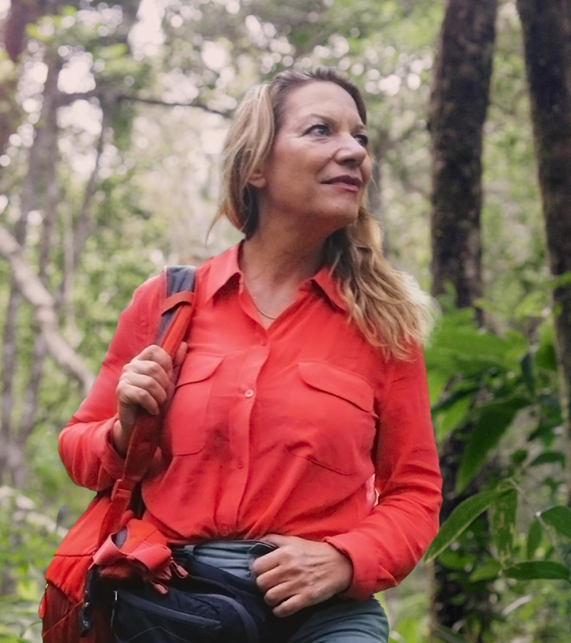 Die Systemforscherin Antje Boetius steht im Regenwald. Sie trägt eine große Umhängetasche und schaut zur Seite.