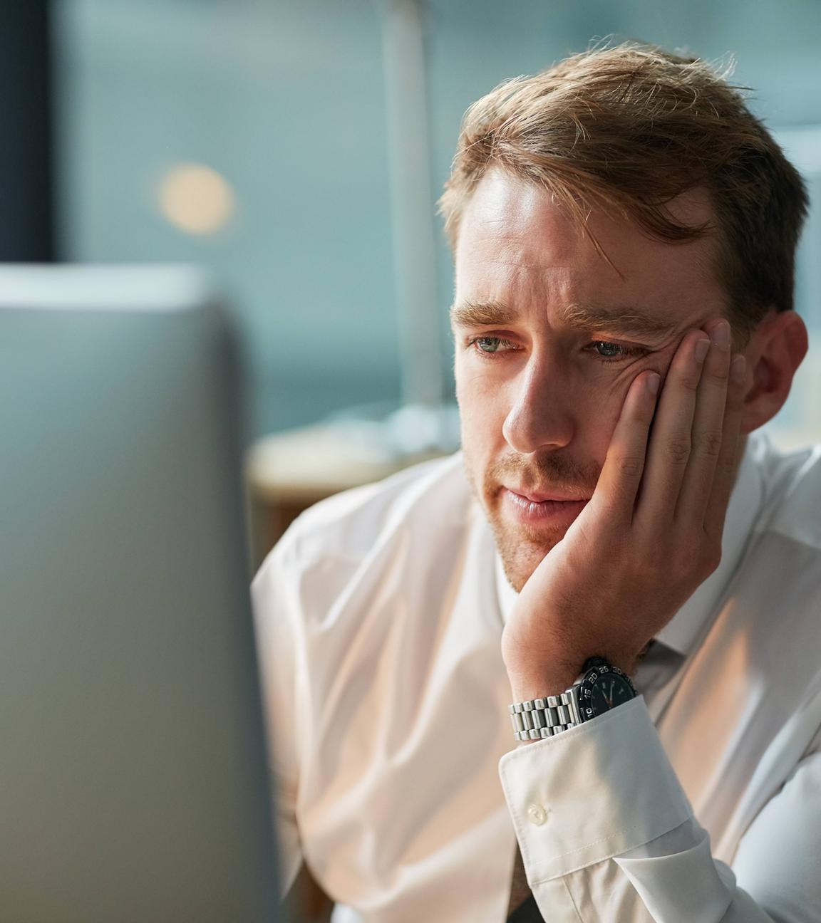 Ein Mann in einem Büro sitzt vor einem Computer und schaut auf den Bildschirm.