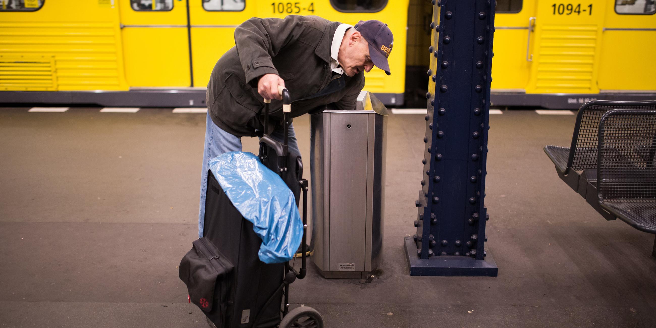 Ein Mann sucht auf einem U-Bahnhof in Berlin nach Pfandflaschen.