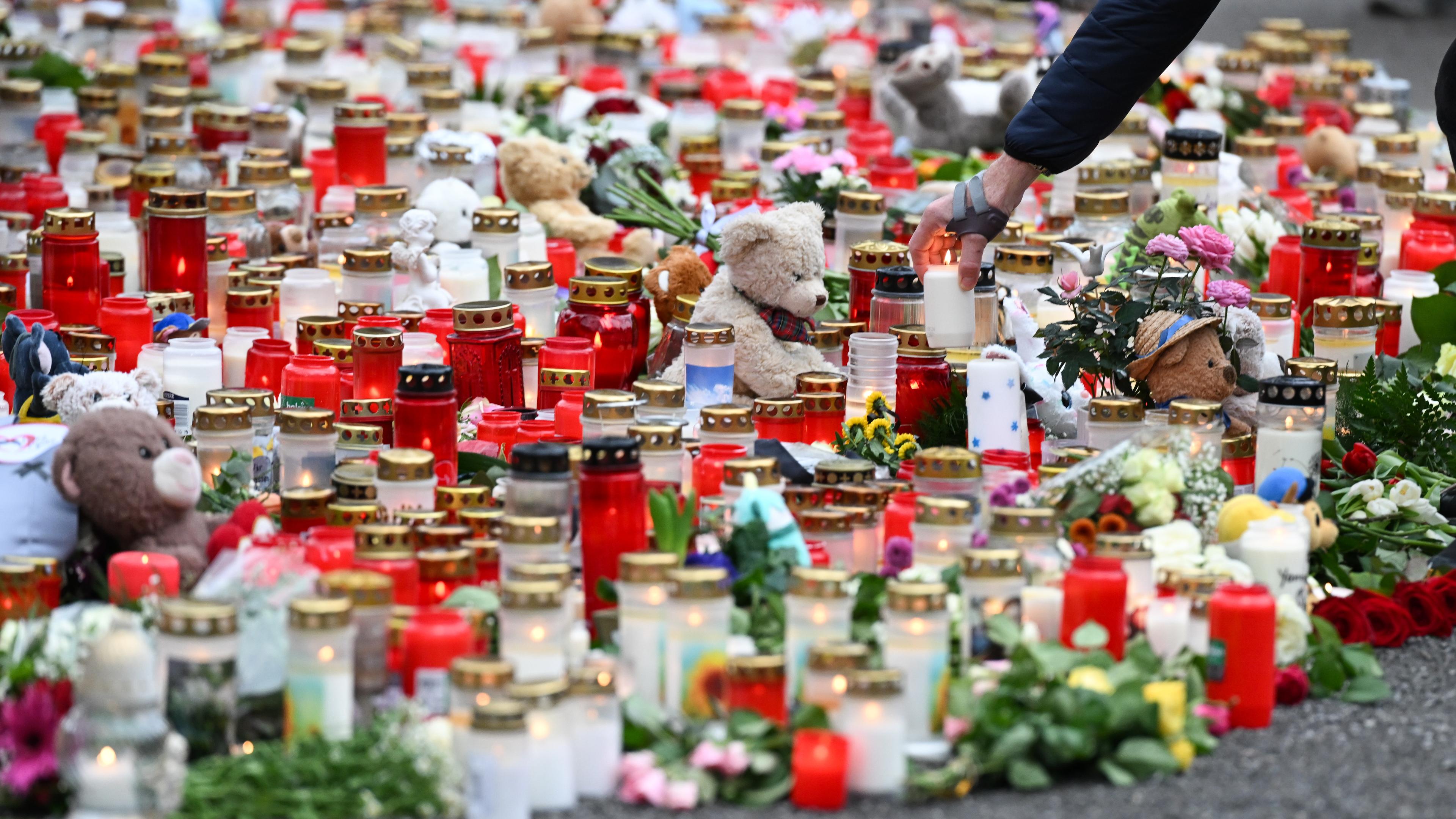 Ein Mann stellt eine Kerze zu zahlreichen anderen Kerzen, Blumen und Plüschtieren im Park Schöntal als Zeichen der Anteilnahme. In dem Park waren am 22.01.2025 ein zweijähriger Junge und ein 41-jähriger Mann bei einem Messerangriff getötet sowie weitere Menschen schwer verletzt worden.