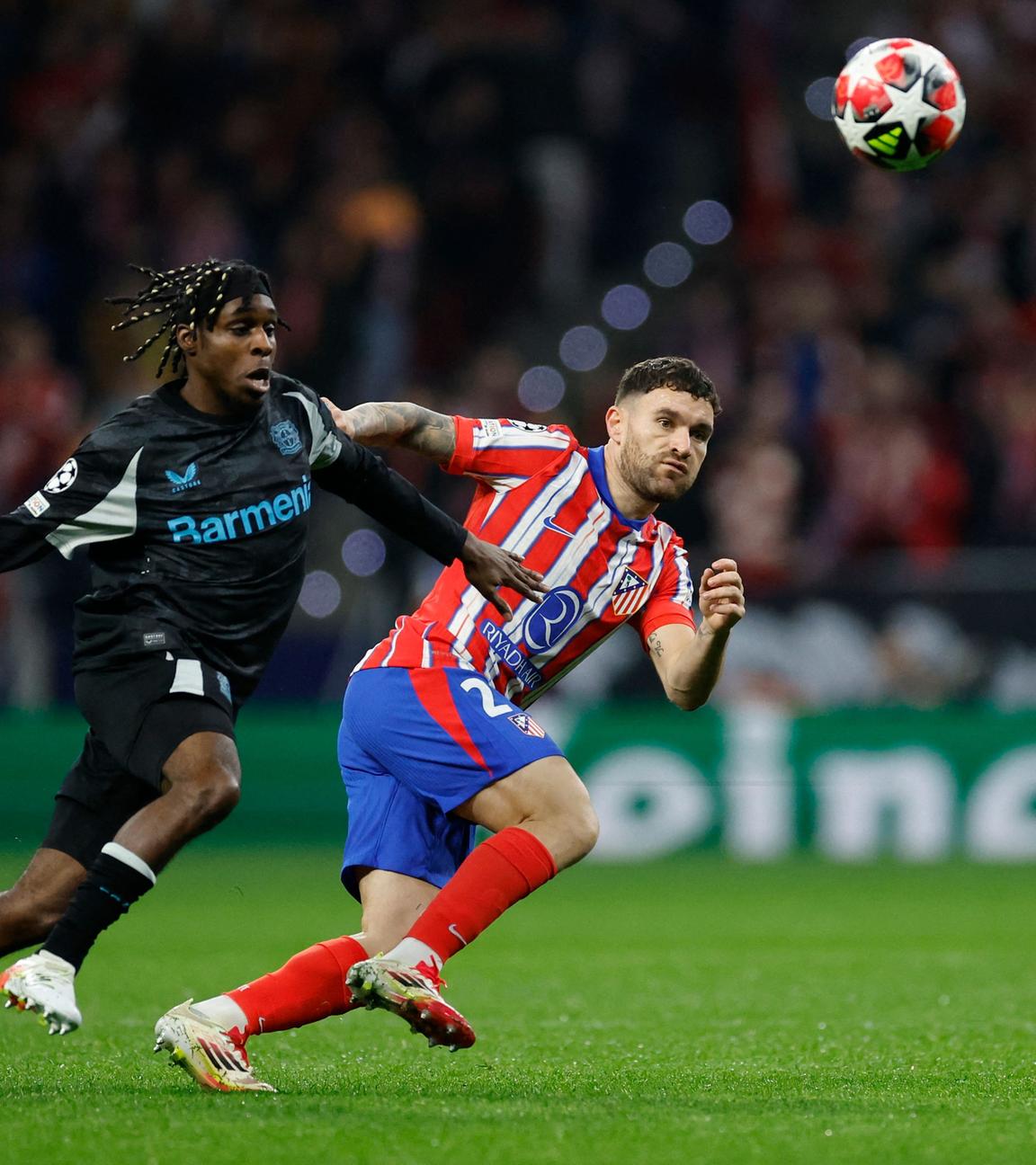 Leverkusens Jeremie Frimpong (l.) und Atletico Madrids Javi Galan kämpfen um den Ball.