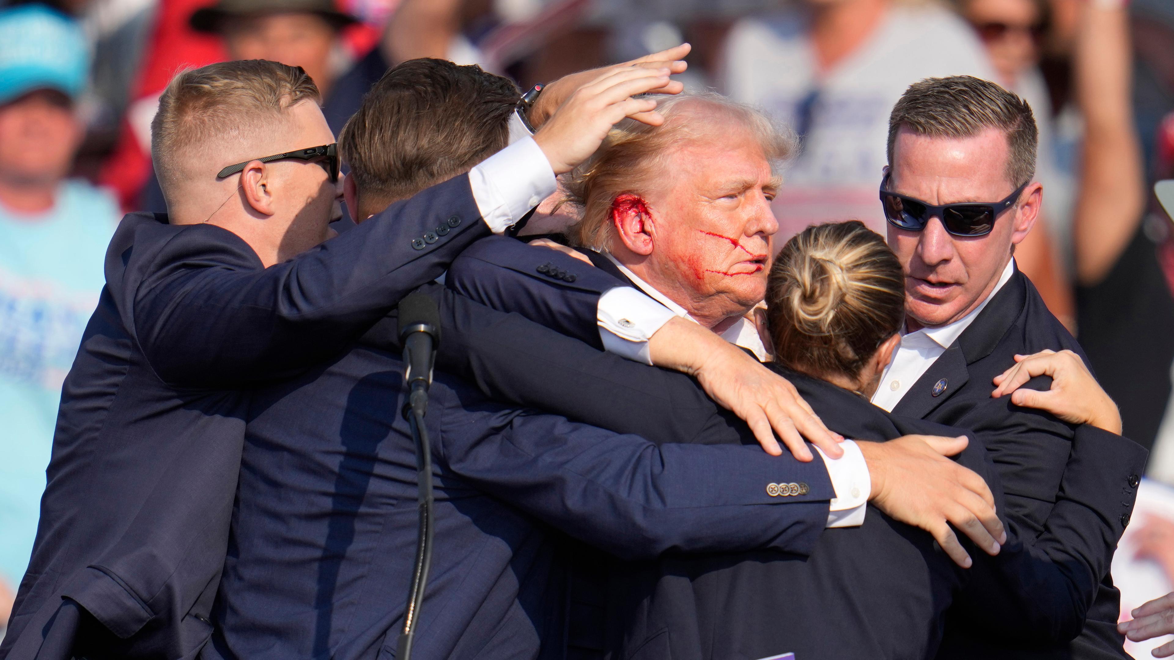 Der republikanische Präsidentschaftsbewerber und frühere US-Präsident Donald Trump wird von Agenten des US-Geheimdienstes Secret Service umringt, als ihm bei einer Wahlkampfveranstaltung von der Bühne geholfen wird. 