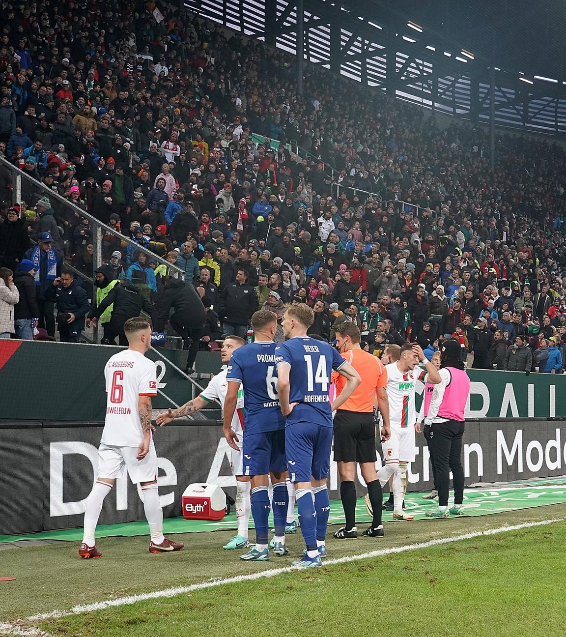 Beide Mannschaften und Schiedsrichter Dr. Felix Brych stehen am 11.11.2023 nach einem Böllerwurf aus dem Hoffenheimer Fanblock vor der Tribüne.