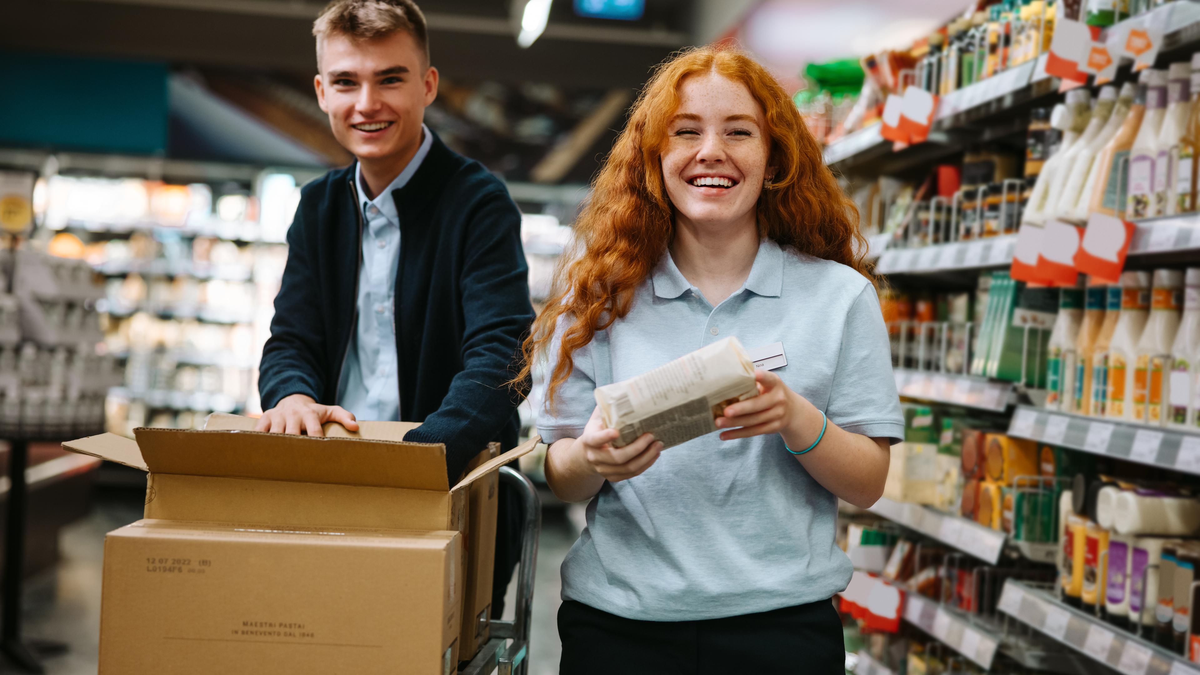 Junger Mann und junge Frau machen im Supermarkt Ausbildung zu Kaufleuten im Einzelhandel