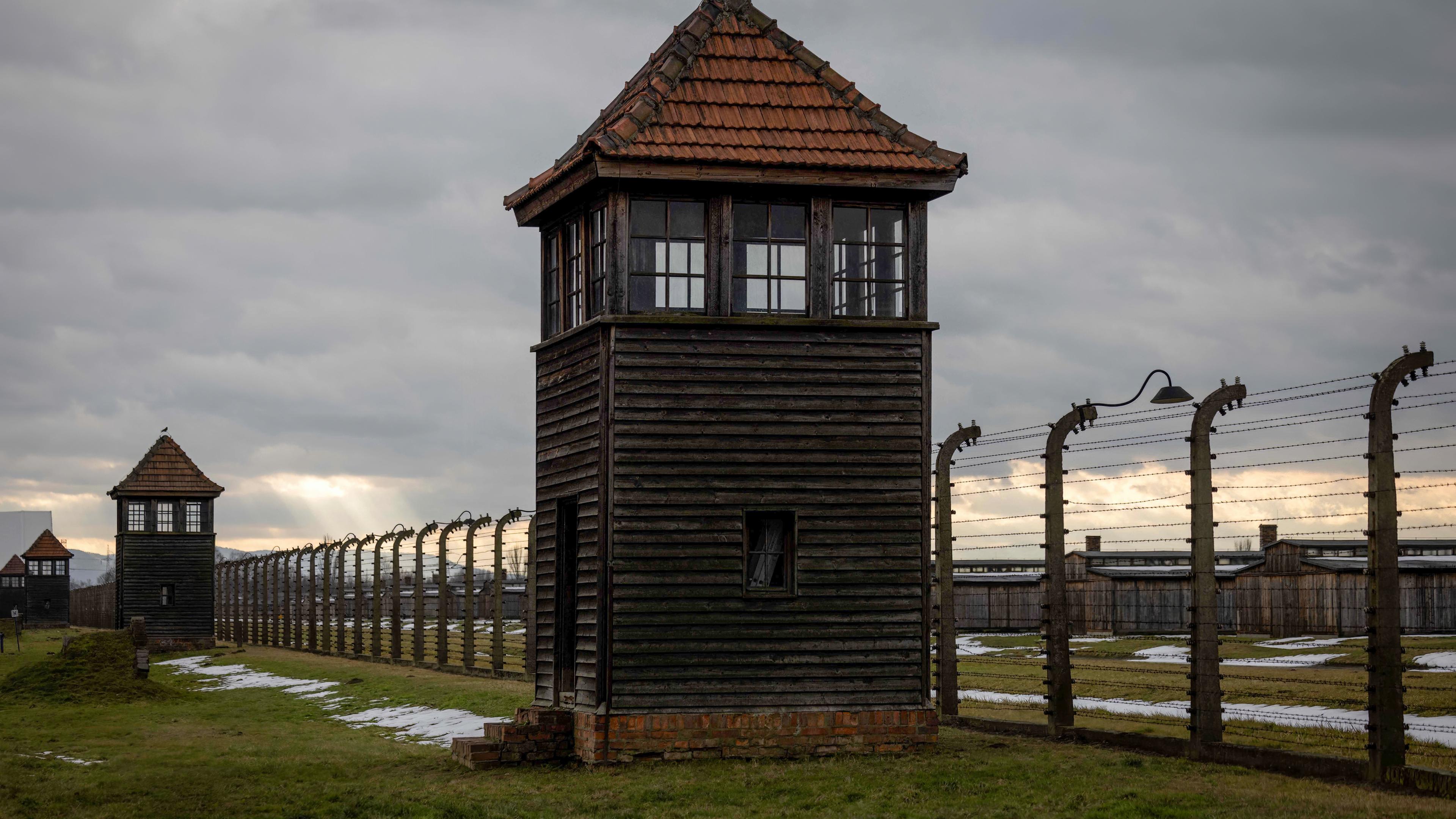 Der Stacheldraht-Zaun vor dem Konzetrationslager Auschwitz mit einem Wachturm.