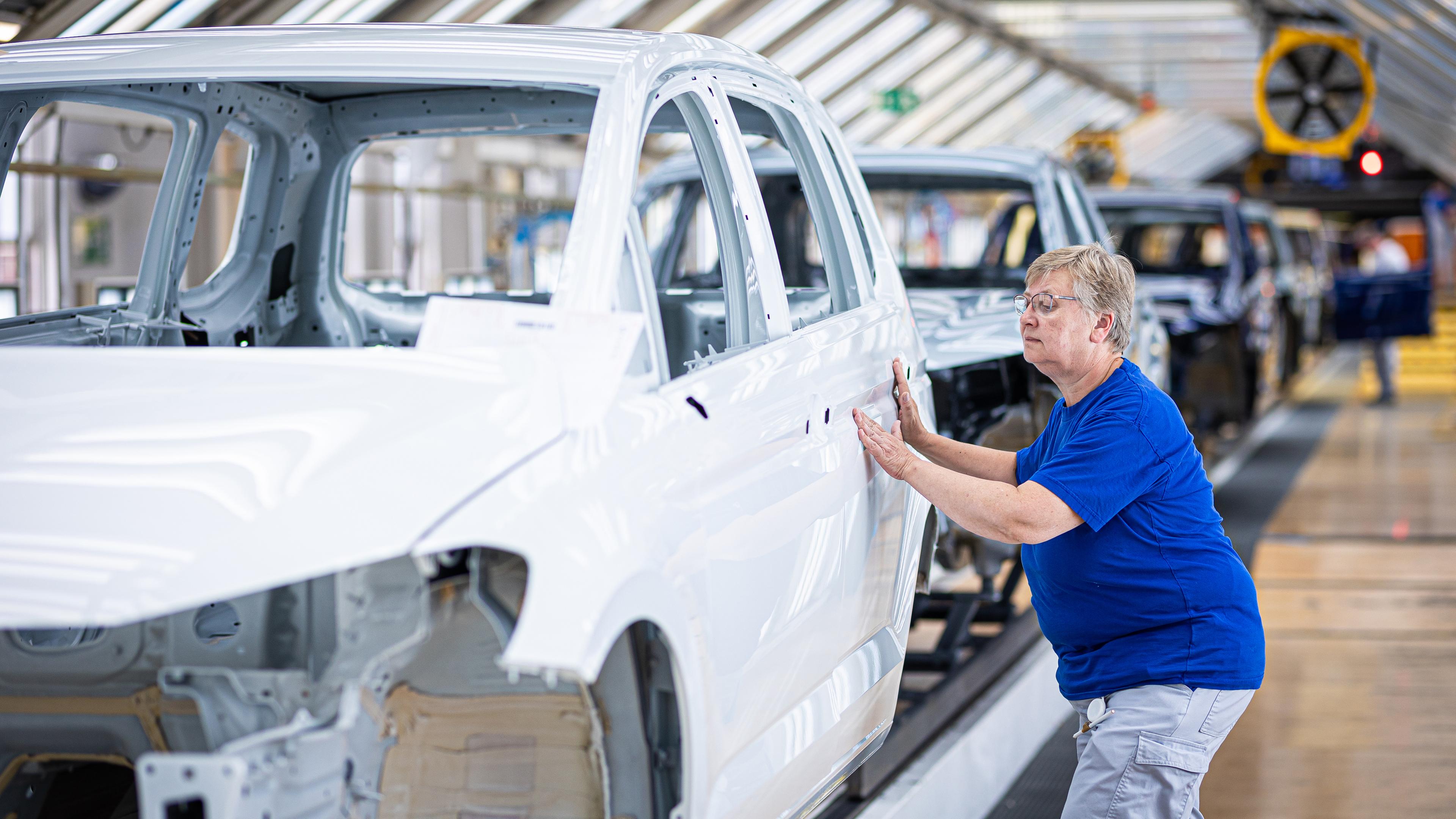 Niedersachsen, Wolfsburg: Eine Mitarbeiterin überprüft im Lichttunnel einer Autofabrik den Lack von Karosserien.