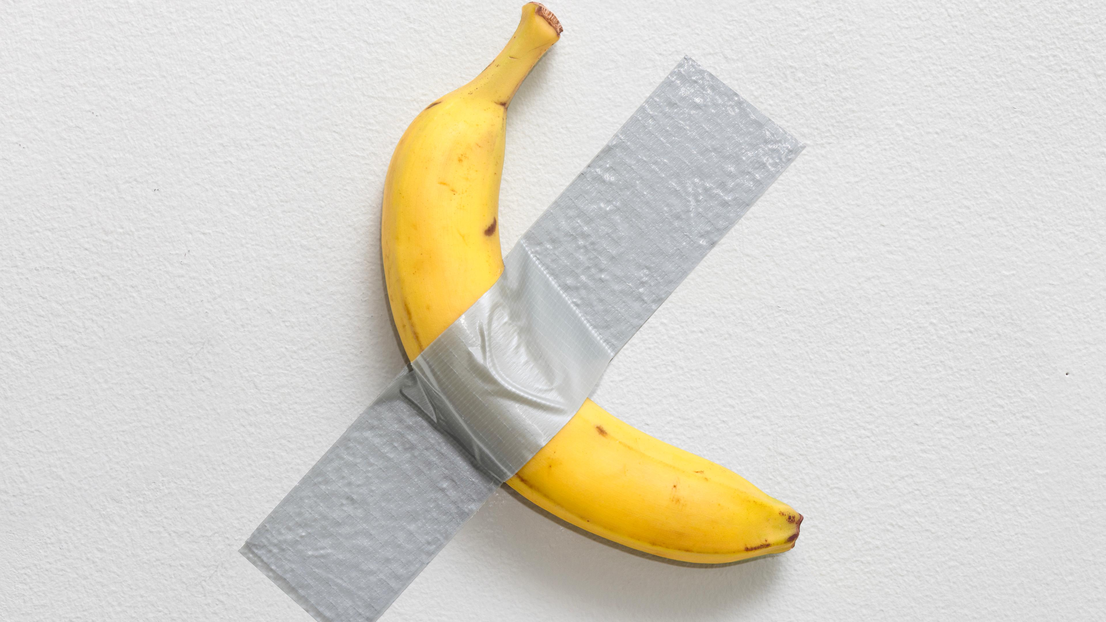 Eine Banane klebt mit Klebeband auf einer Wand.