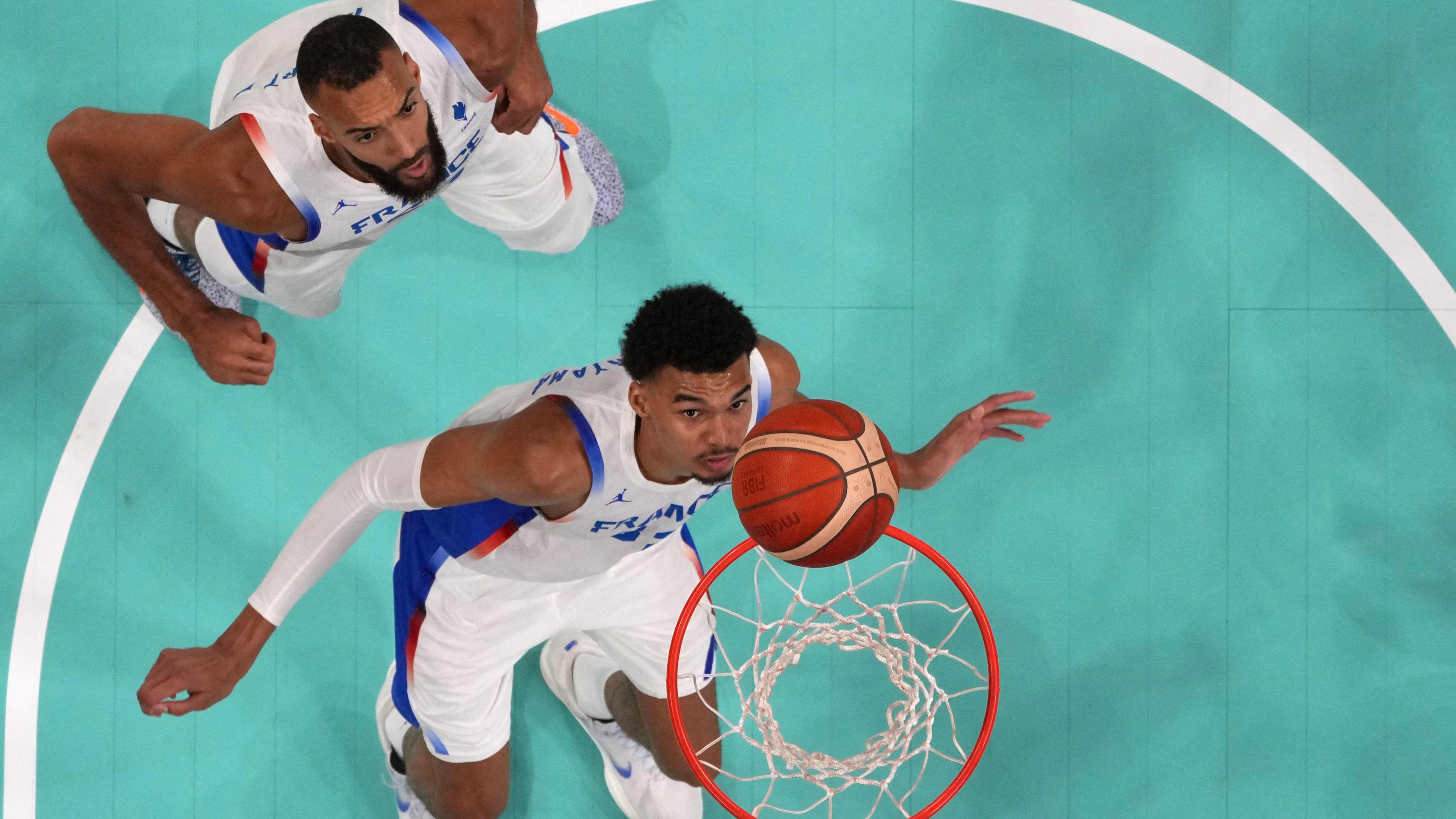 Frankreichs Basketballer Rudy Gobert (l) und Victor Wembanyama unter dem Korb