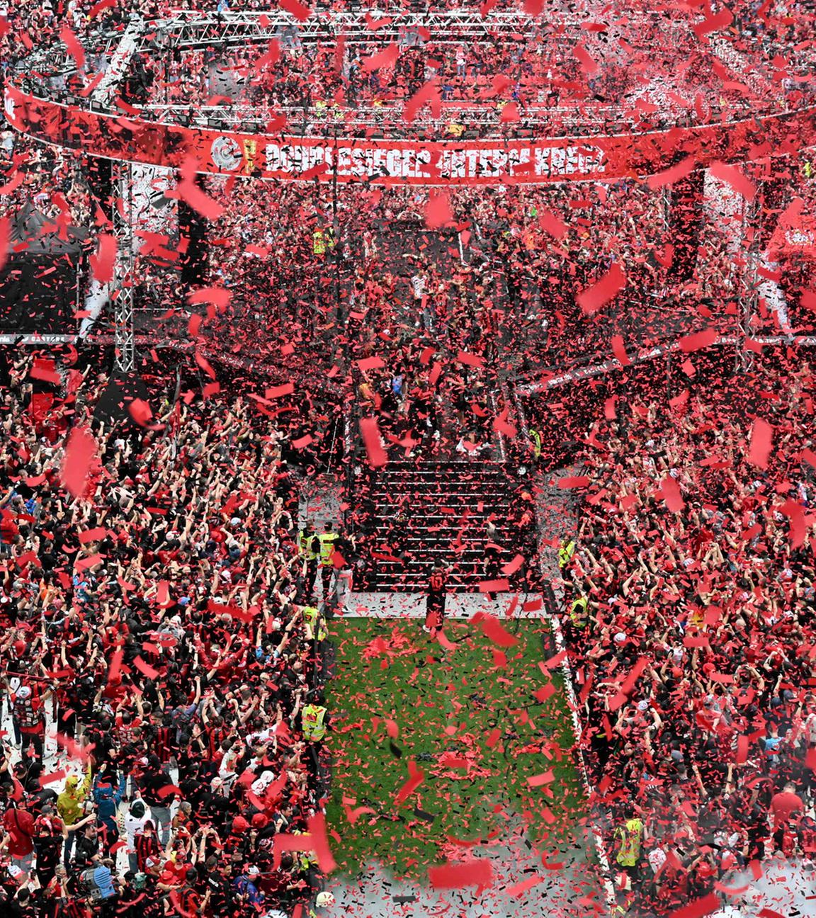 Spieler und Fans von Bayer Leverkusen feiern den Gewinn der Bundesliga und des DFB-Pokals im Stadion während der Siegesfeier.
