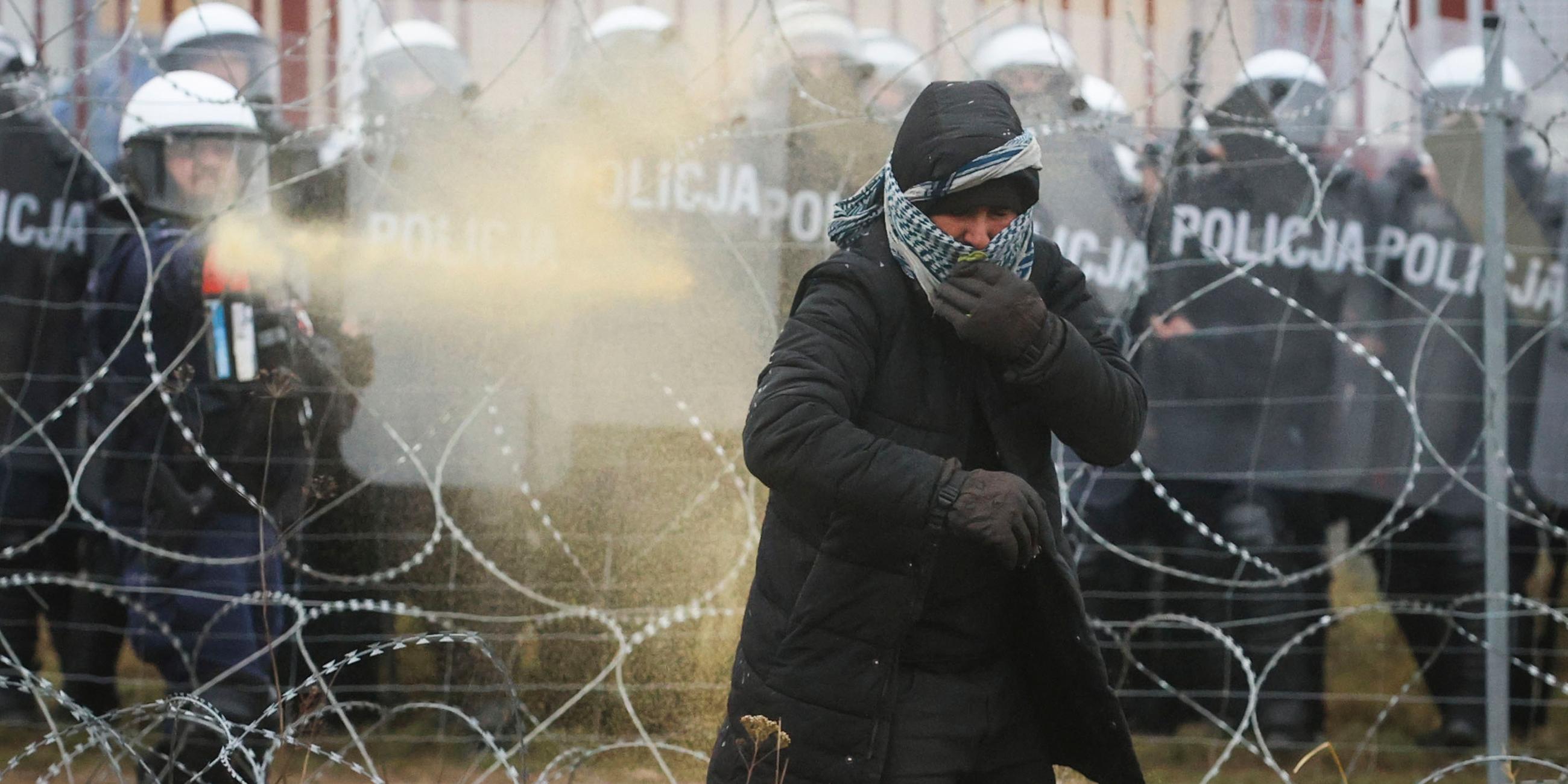 Eine Frau verfängt sich im Stacheldraht und wird von der Grenzpolizei mit Pfefferspray am Weiterkommen gehindert.