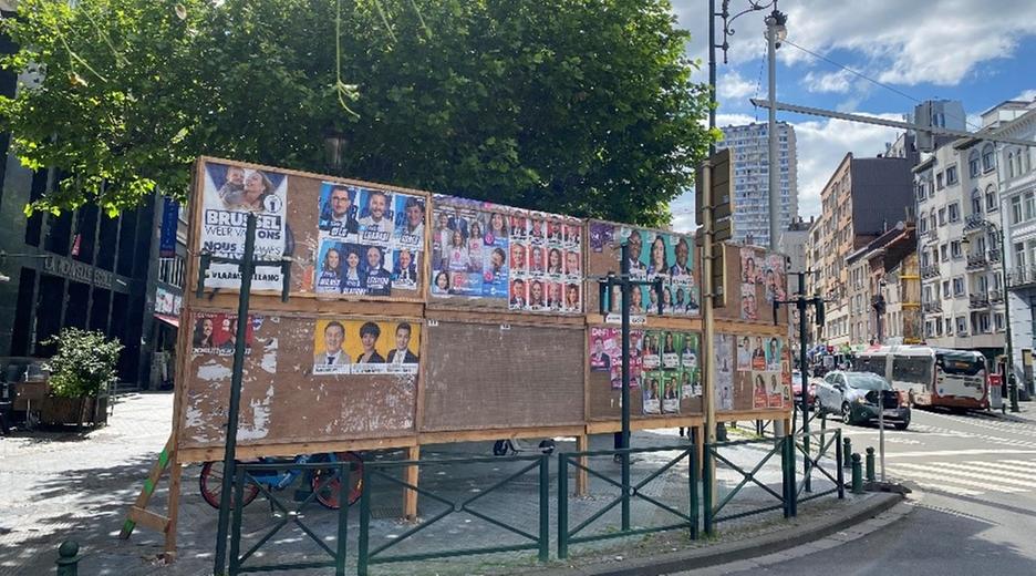 Auf einer Plakatwand in Belgien sind Wahlplakate verschiedener Kandidatinnen und Kandidaten zu sehen.