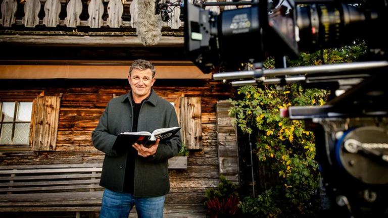 Der Bergdoktor Hans Sigl am Set der Serienproduktion mit einem Buch in der Hand.