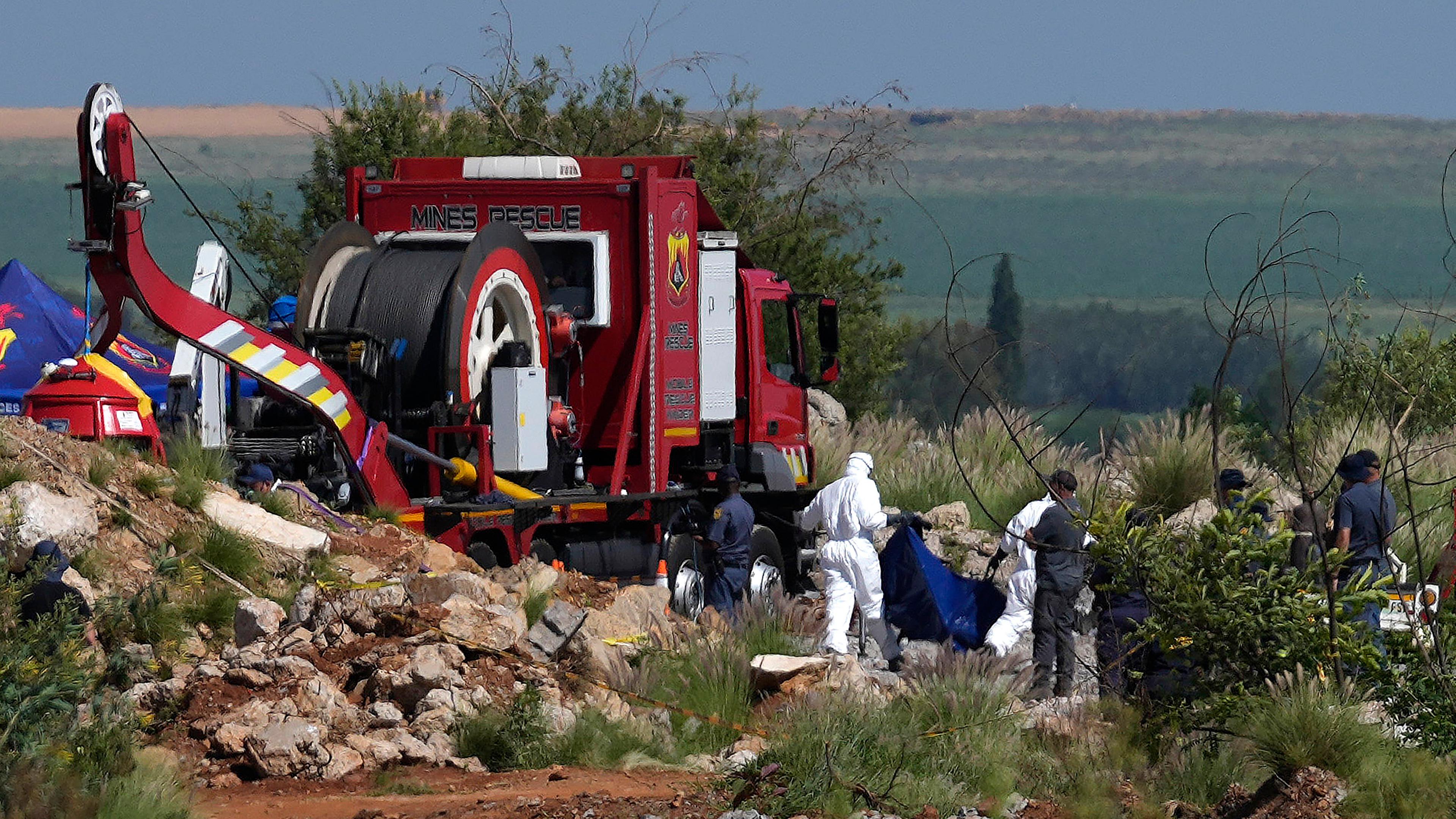 Südafrika, Stilfontein: Gerichtsmediziner tragen die menschliche Überreste in blauen Leichensäcken während einer Rettungsaktion zur Bergung von Bergleuten unter Tage in einer verlassenen Goldmine.