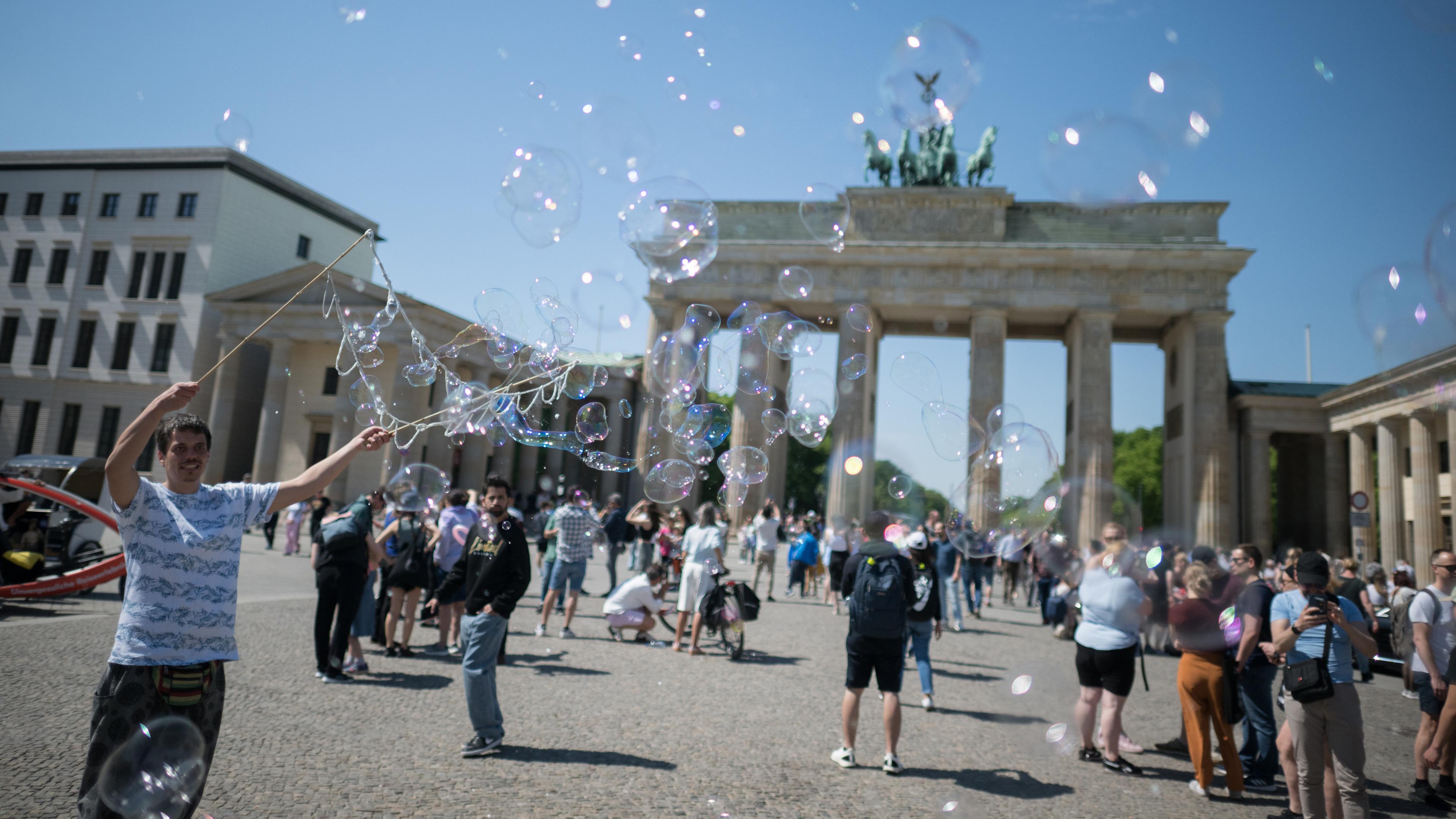 Berlin: Ein Mann produziert Seifenblasen vor dem Brandenburger Tor.