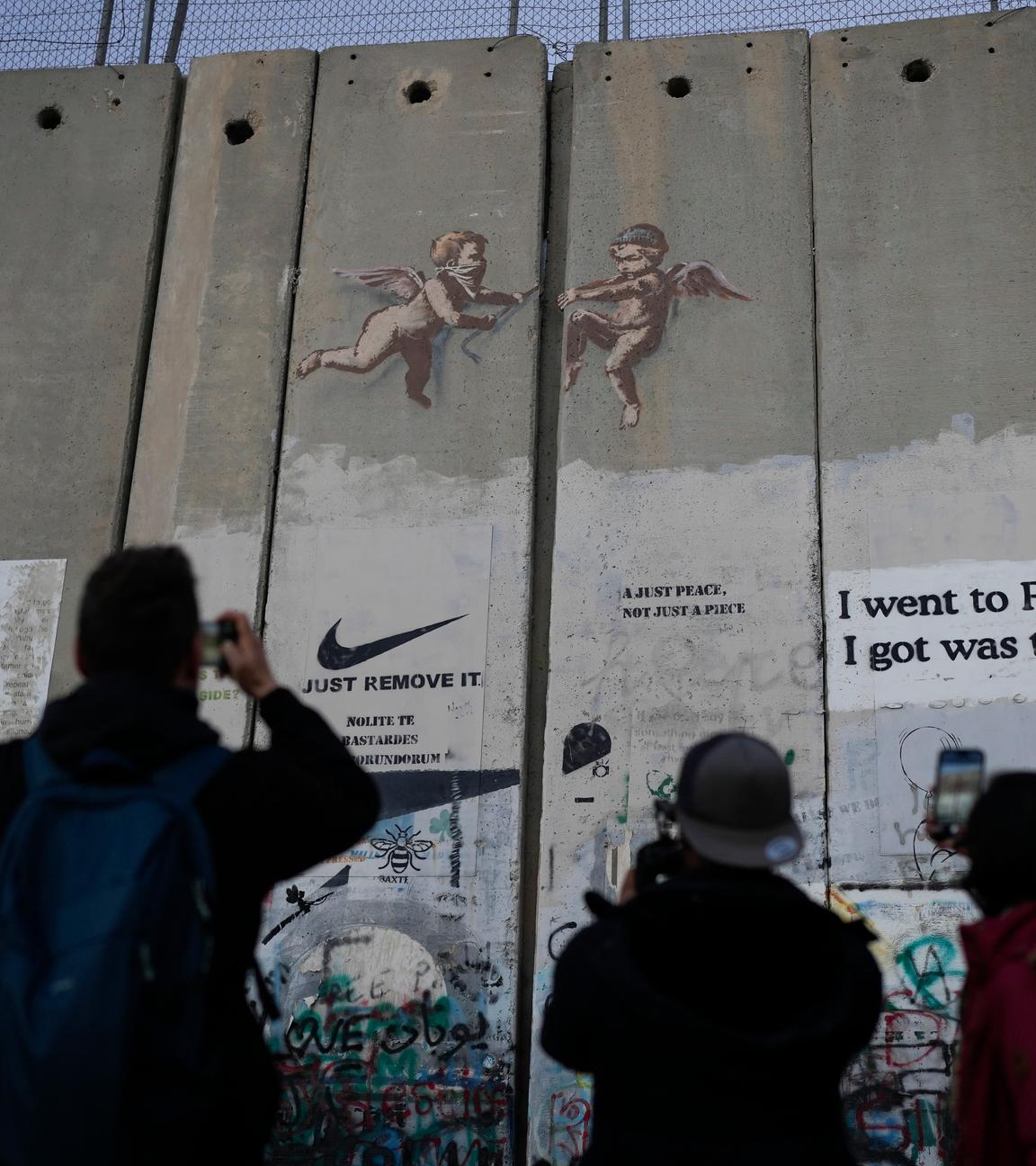 Touristen fotografieren an Heiligabend ein Banksy-Graffiti auf der Trennmauer in Bethlehem im Westjordanland