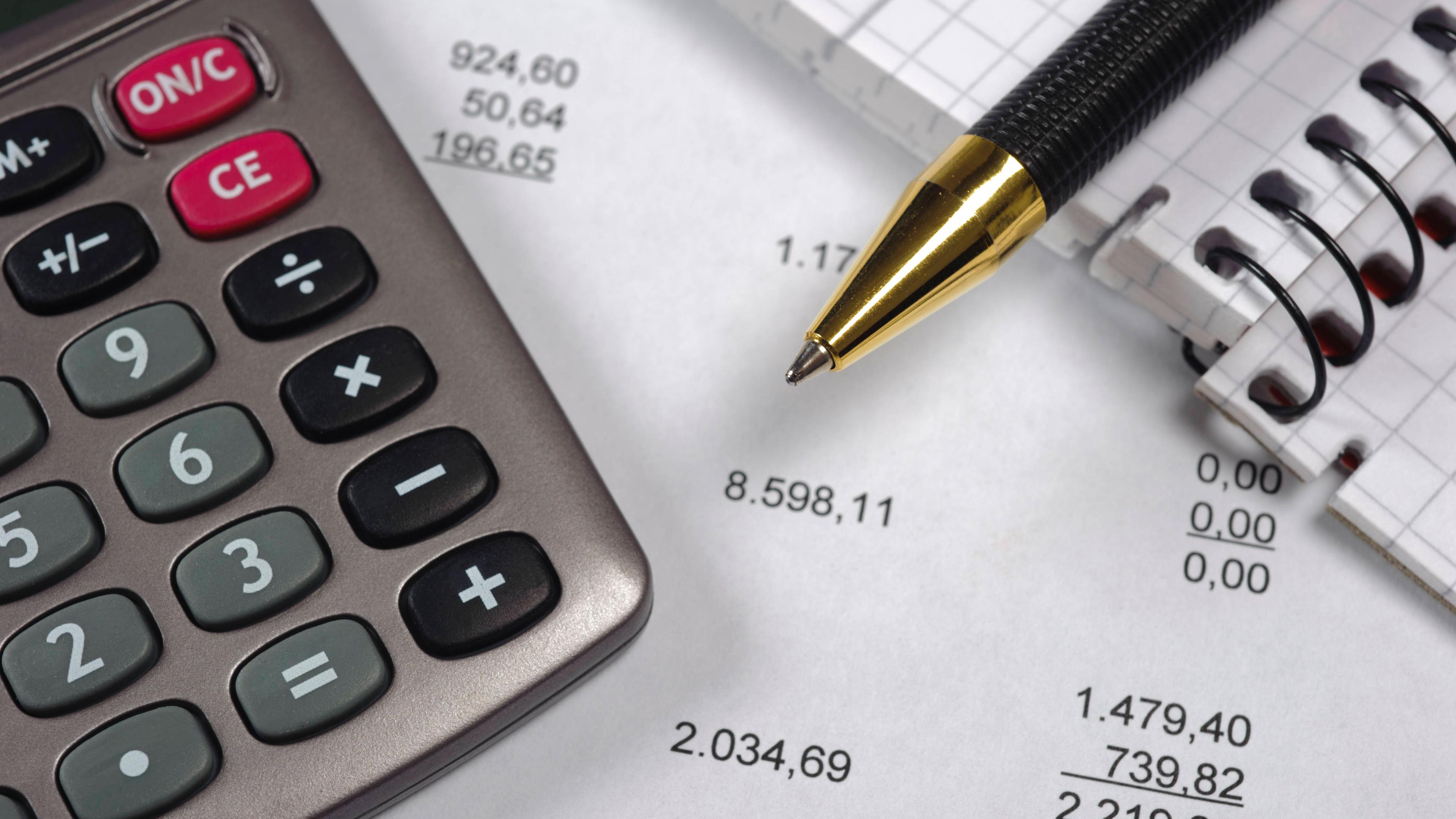 Ein Taschenrechner und ein Kugelschreiber liegen auf einer ausgedruckten Gehaltsabrechnung.