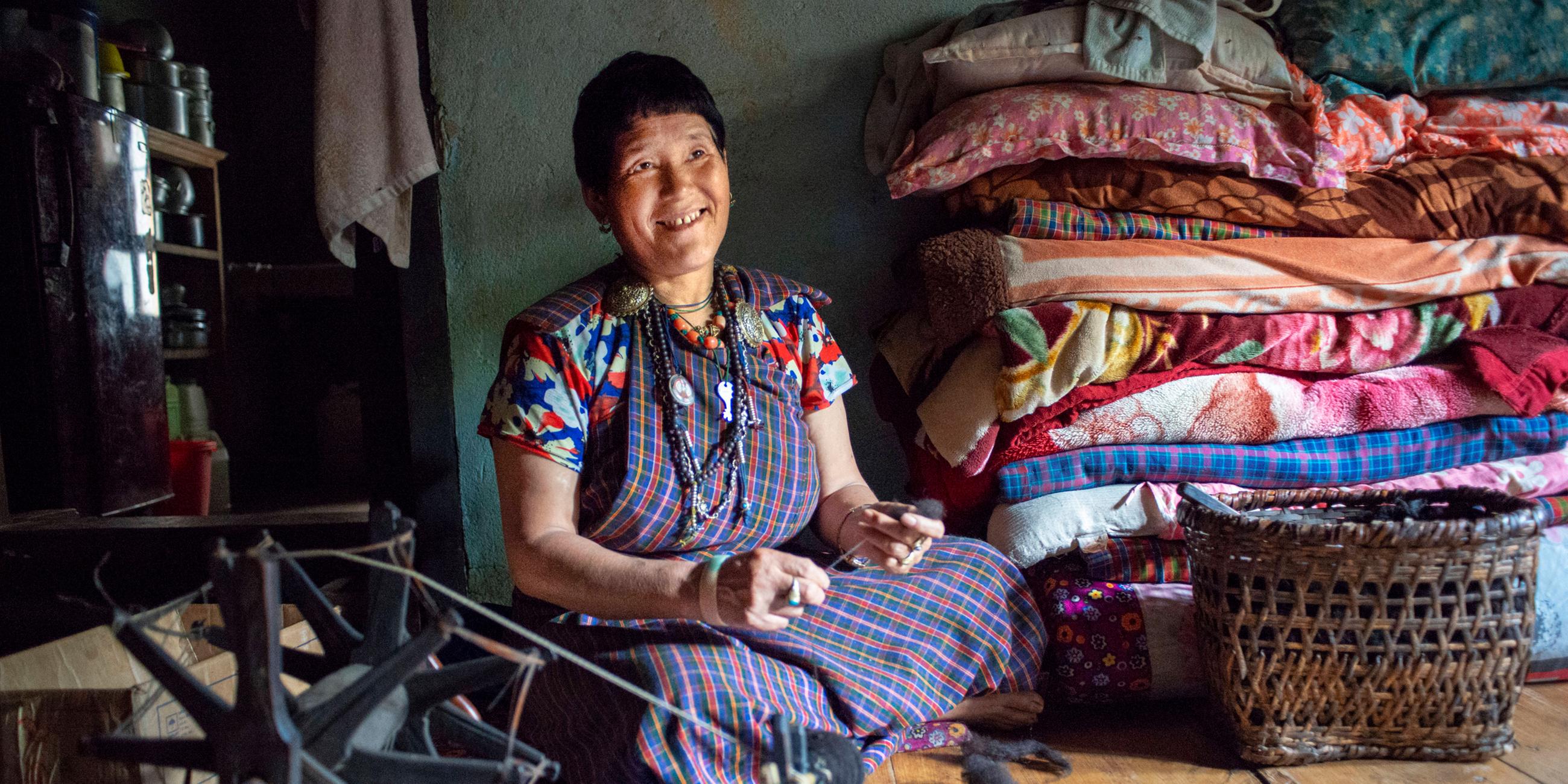 Eine Frau näht Kleidung in ihrem Haus in einem Dorf in Bhutan