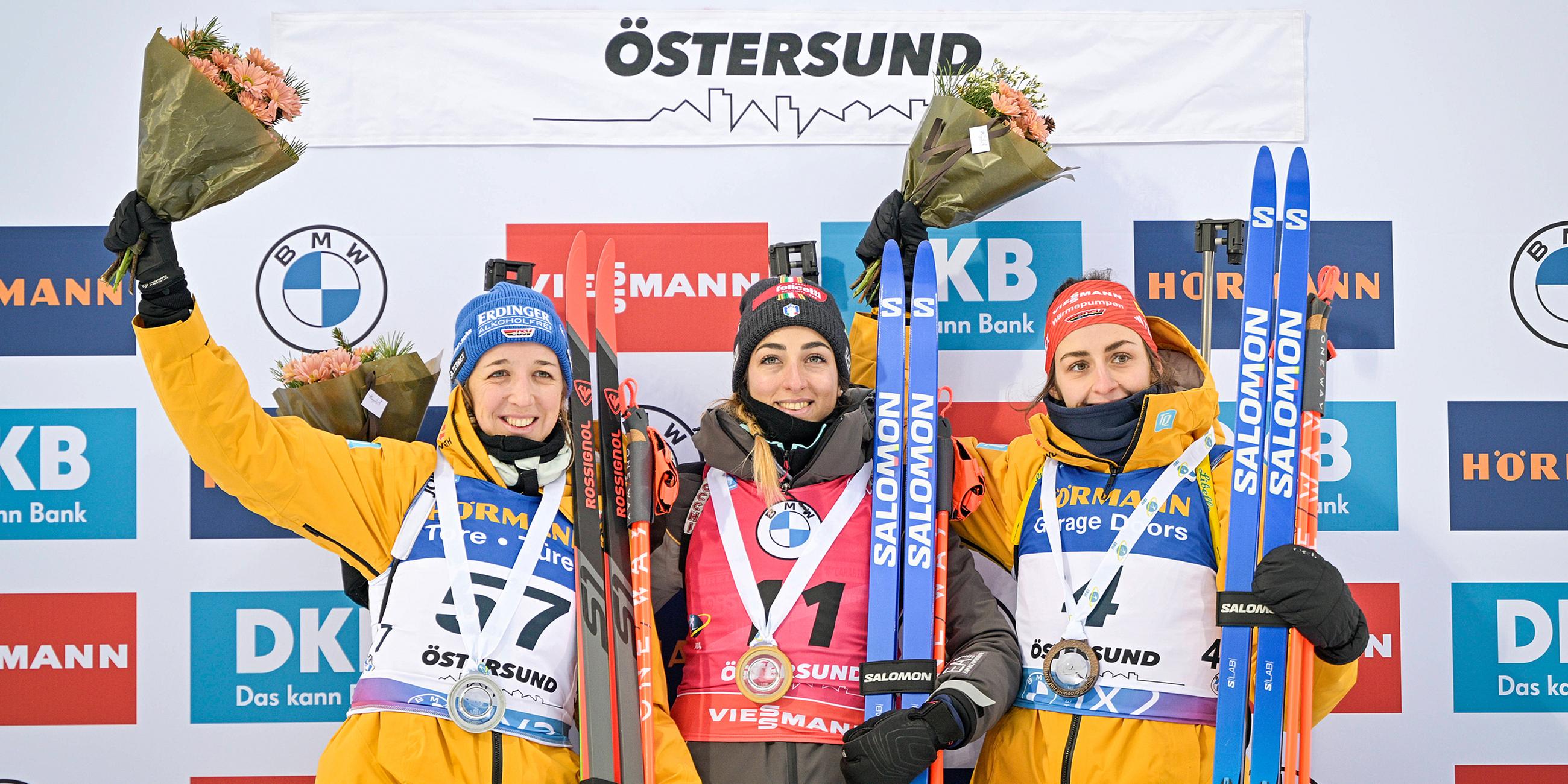 Lisa Vittozzi (m.), Franziska Preuss (l.) und Vanessa Voigt (r.) bei der Siegerehrung am 26.11.23 in Schweden.
