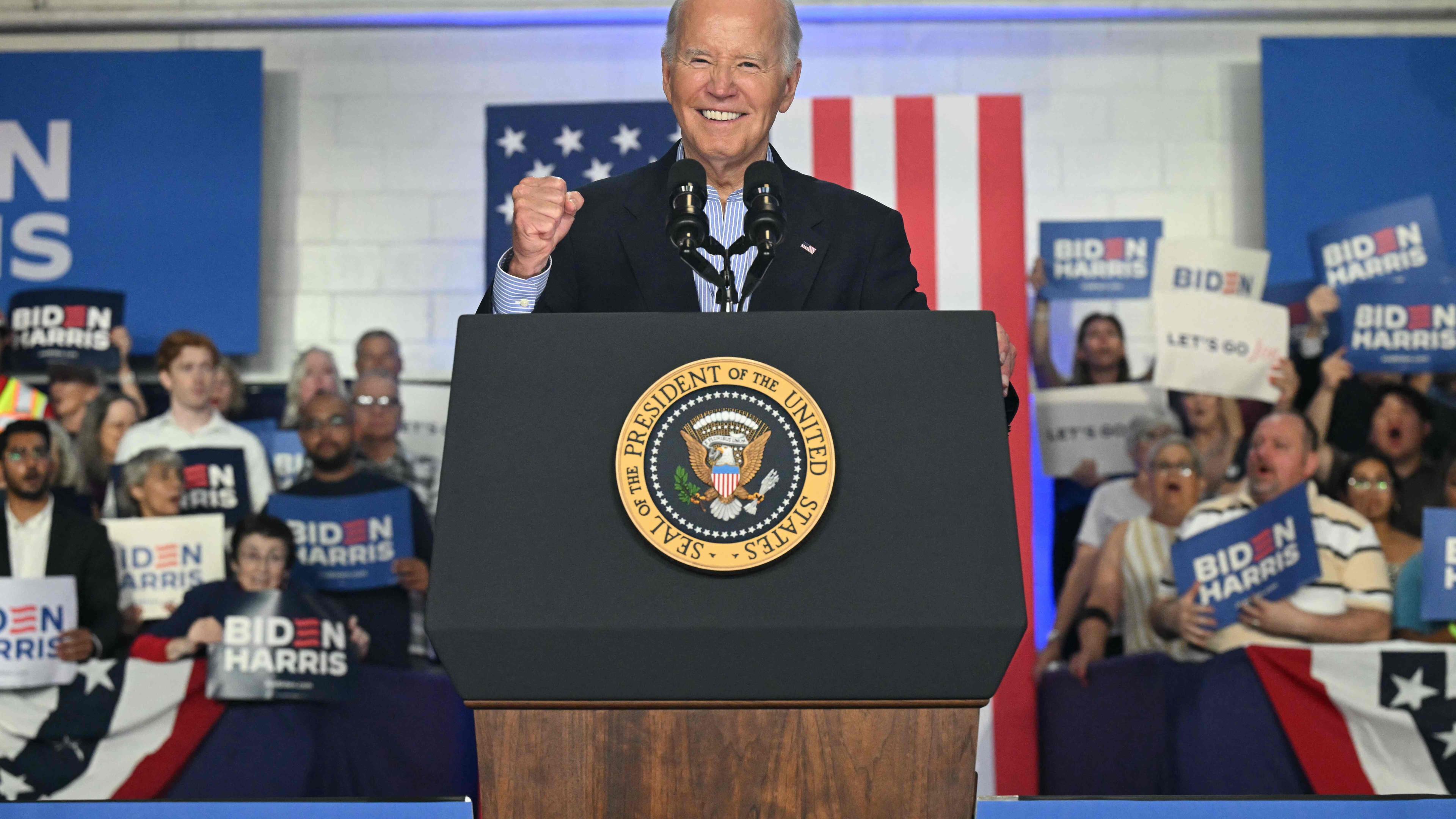 US-Präsident Joe Biden steht bei einer Wahlkampfverantstaltung auf einer Bühne und ballt die Faust und lächelt in die Kamera.