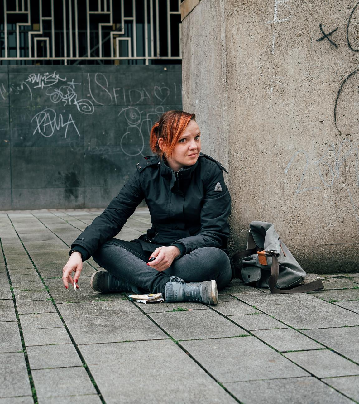 Eine junge obdachlose Frau, die auf dem Boden sitzt.