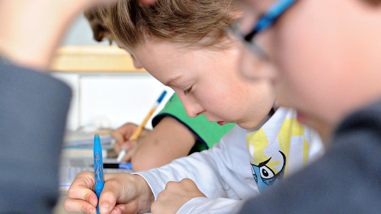 Jungen sitzen in der Schule und schreiben etwas.