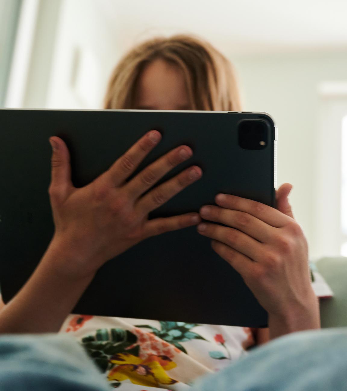 Mädchen sitzt mit Tablet auf dem Sofa