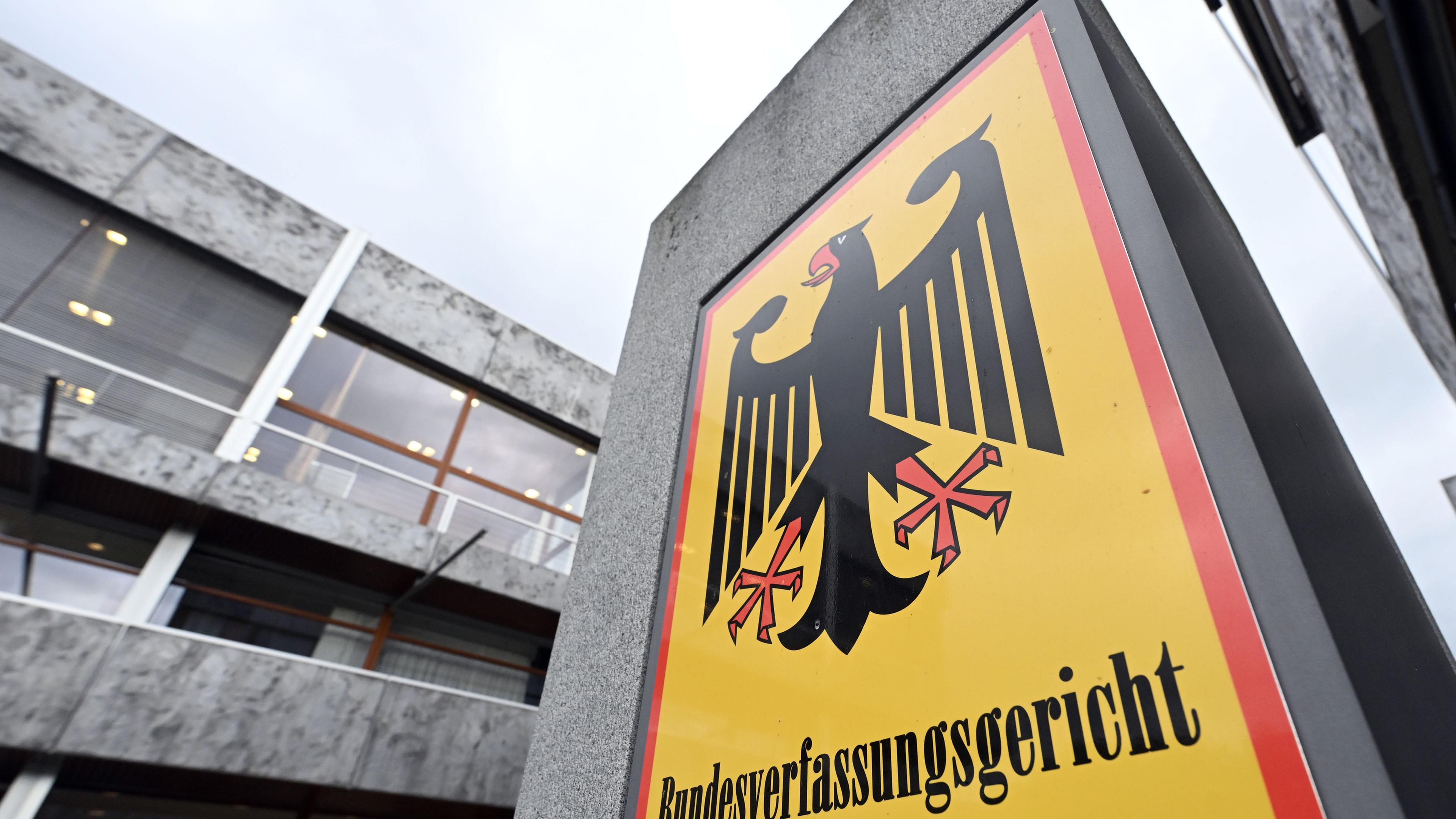 Ein Schild am Platz des Bundesverfassungsgerichts zeigt den Bundesadler in Schwarz, umrahmt von den Farben Schwarz-Rot-Gold der Bundesrepublik Deutschland.