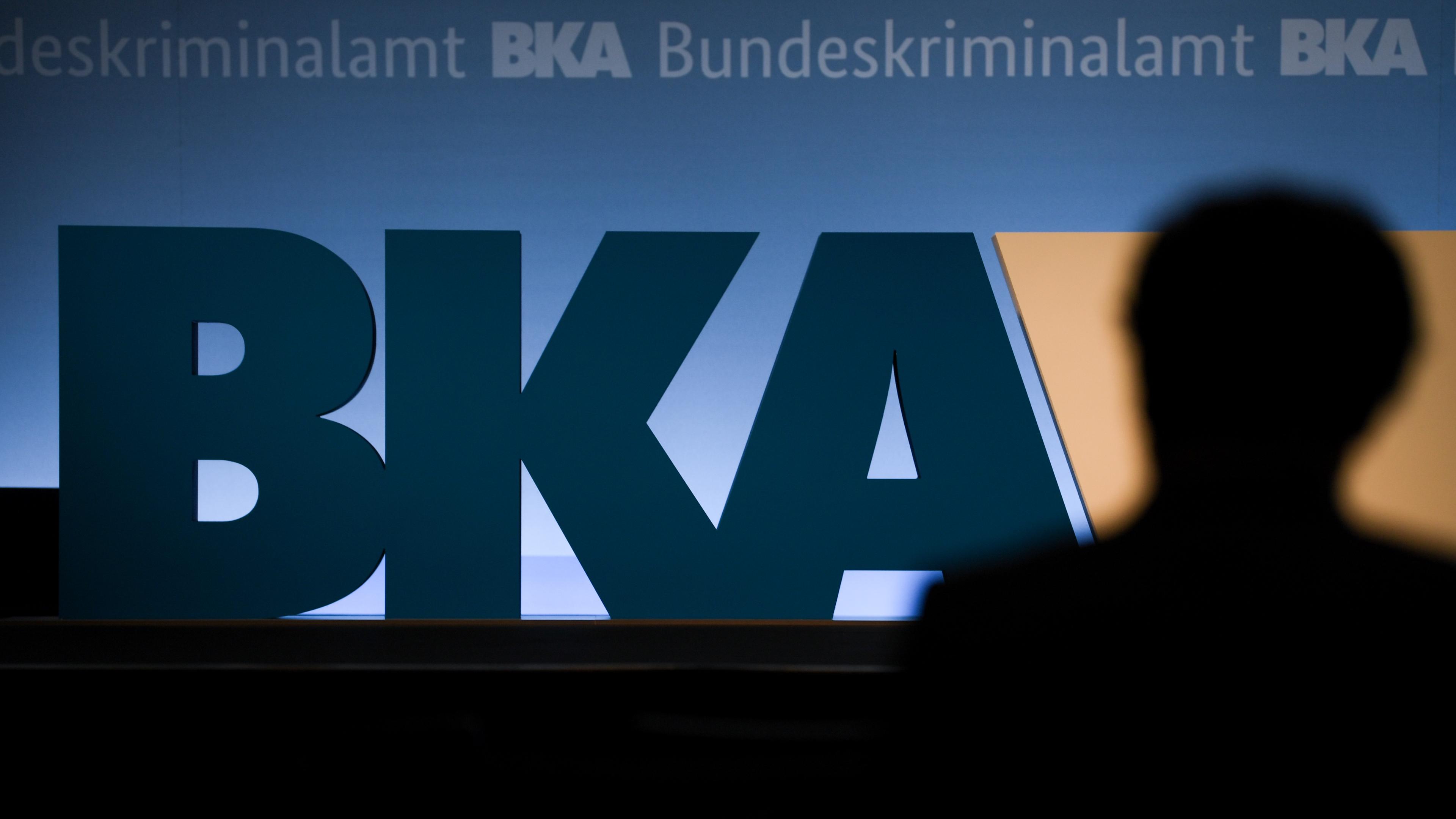 Ein Teilnehmer der BKA-Herbsttagung steht im Veranstaltungssaal vor dem BKA-Logo