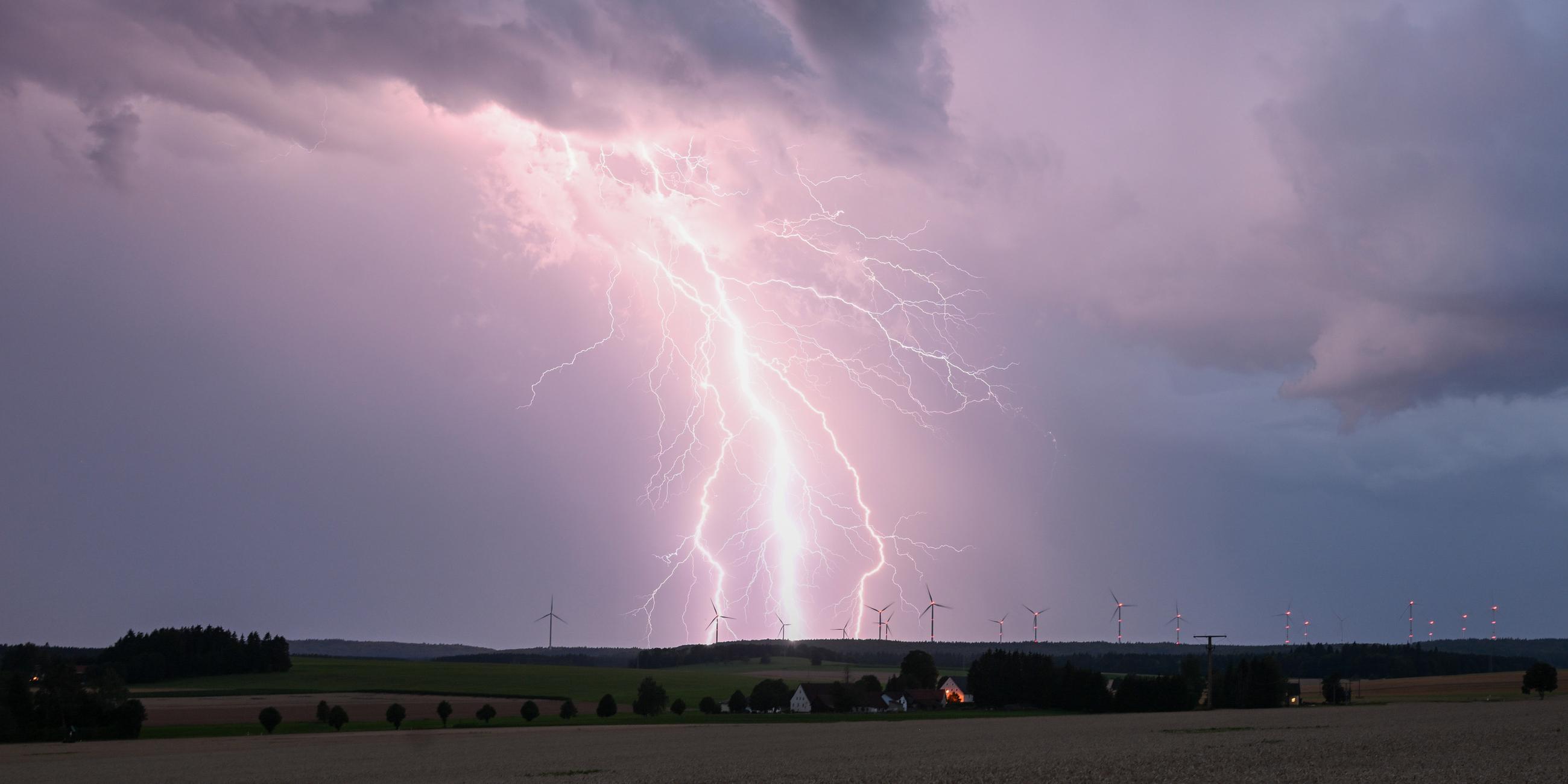 Ein Blitz zuckt bei einem Sommergewitter am abendlichen Himmel