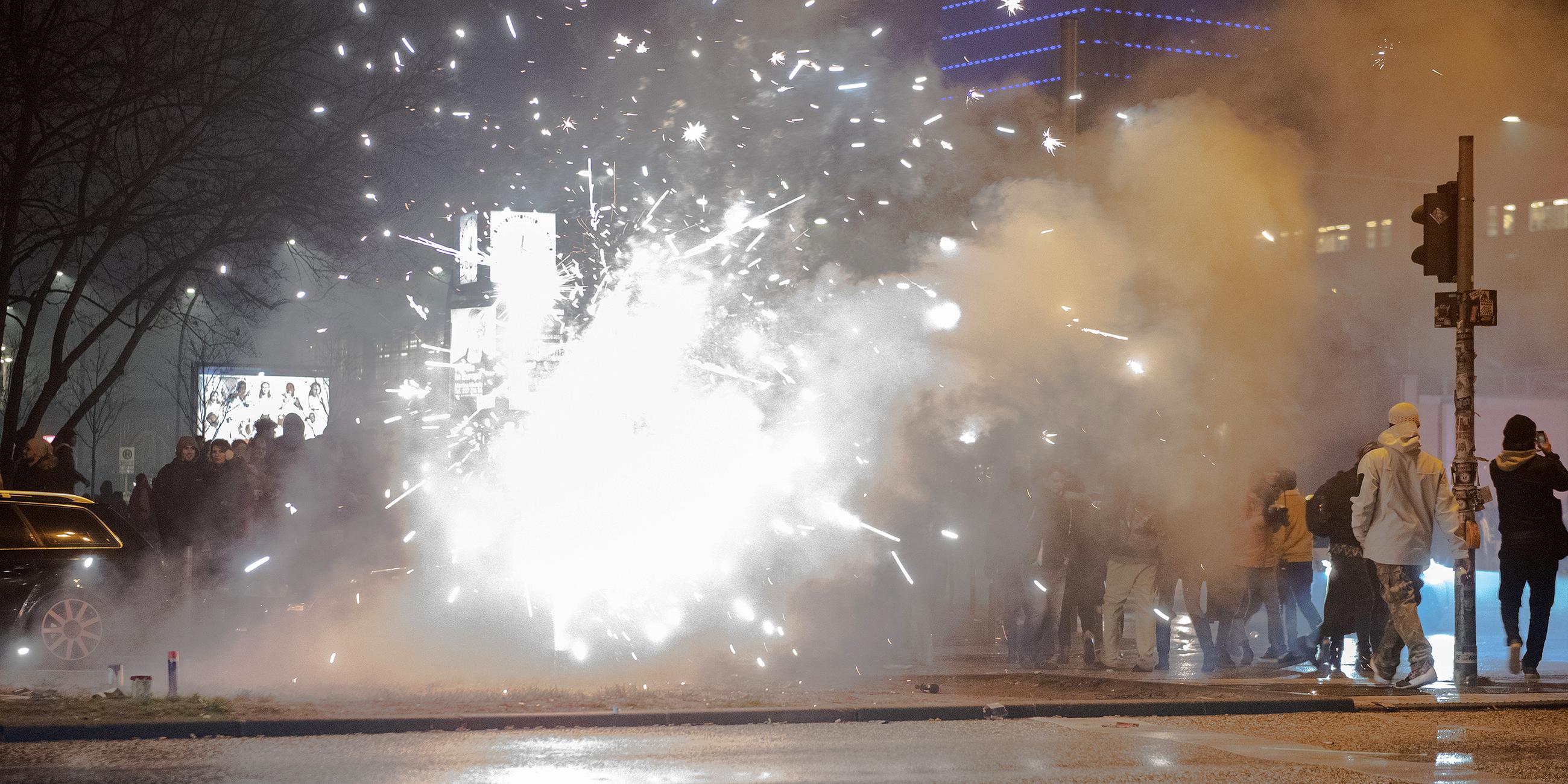 Silvesterböller explodieren in Berlin während Passanten vorbeigehen.