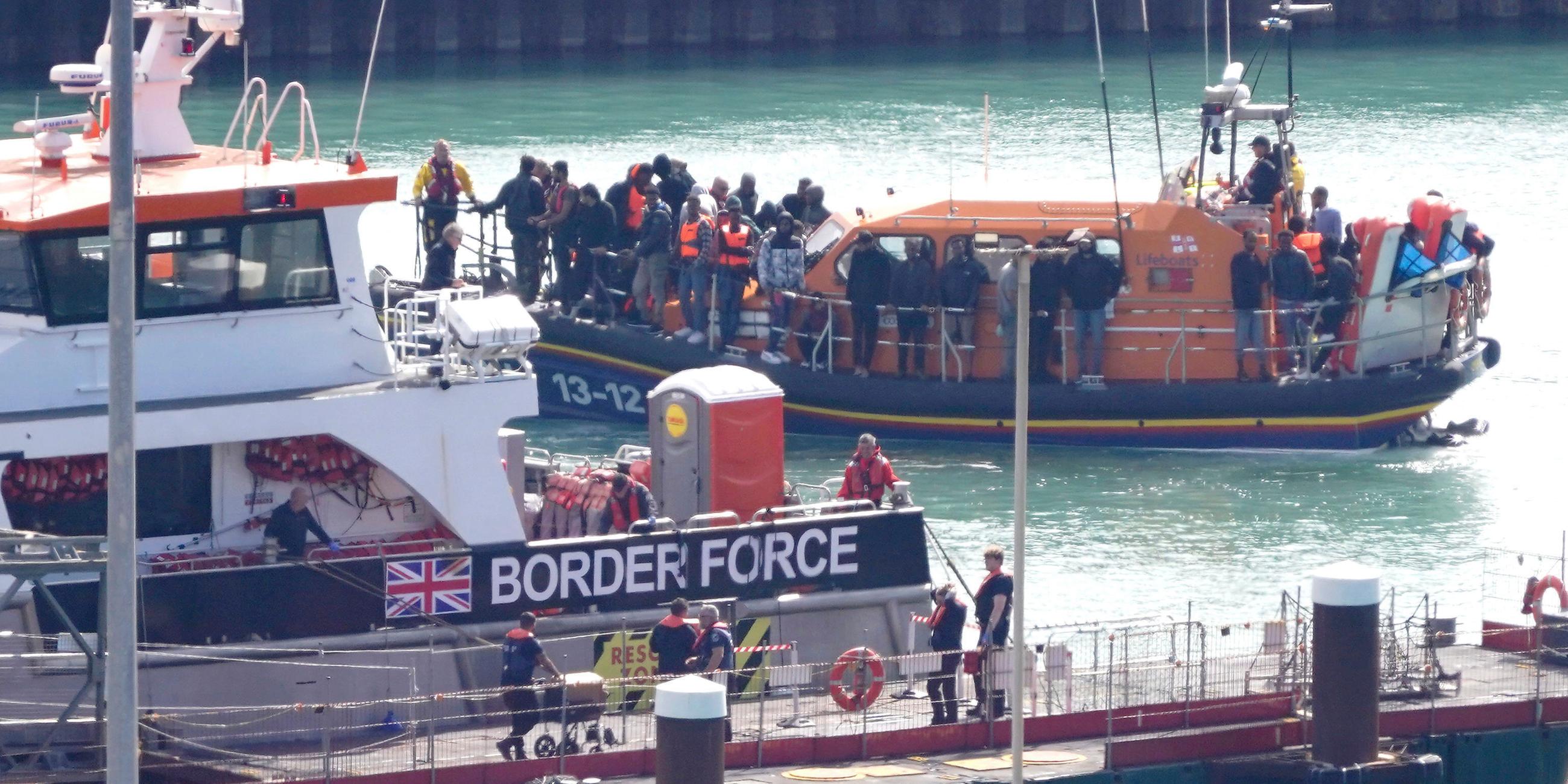 Eine Gruppe von Menschen, bei denen es sich vermutlich um Migranten handelt, wird nach einem Zwischenfall mit einem kleinen Boot im Ärmelkanal an Bord des RNLI-Rettungsboots Dungeness nach Dover (Kent) gebracht.