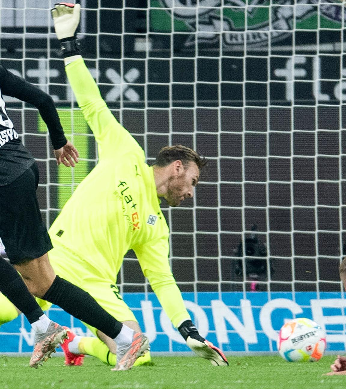 Frankfurts Jesper Lindström (l) trifft gegen Gladbachs Torhüter Tobias Sippel zur 1:0 Führung. Rechts liegt Gladbachs Nico Elvedi auf dem Rasen, am 22.10.2022 in Mönchengladbach.