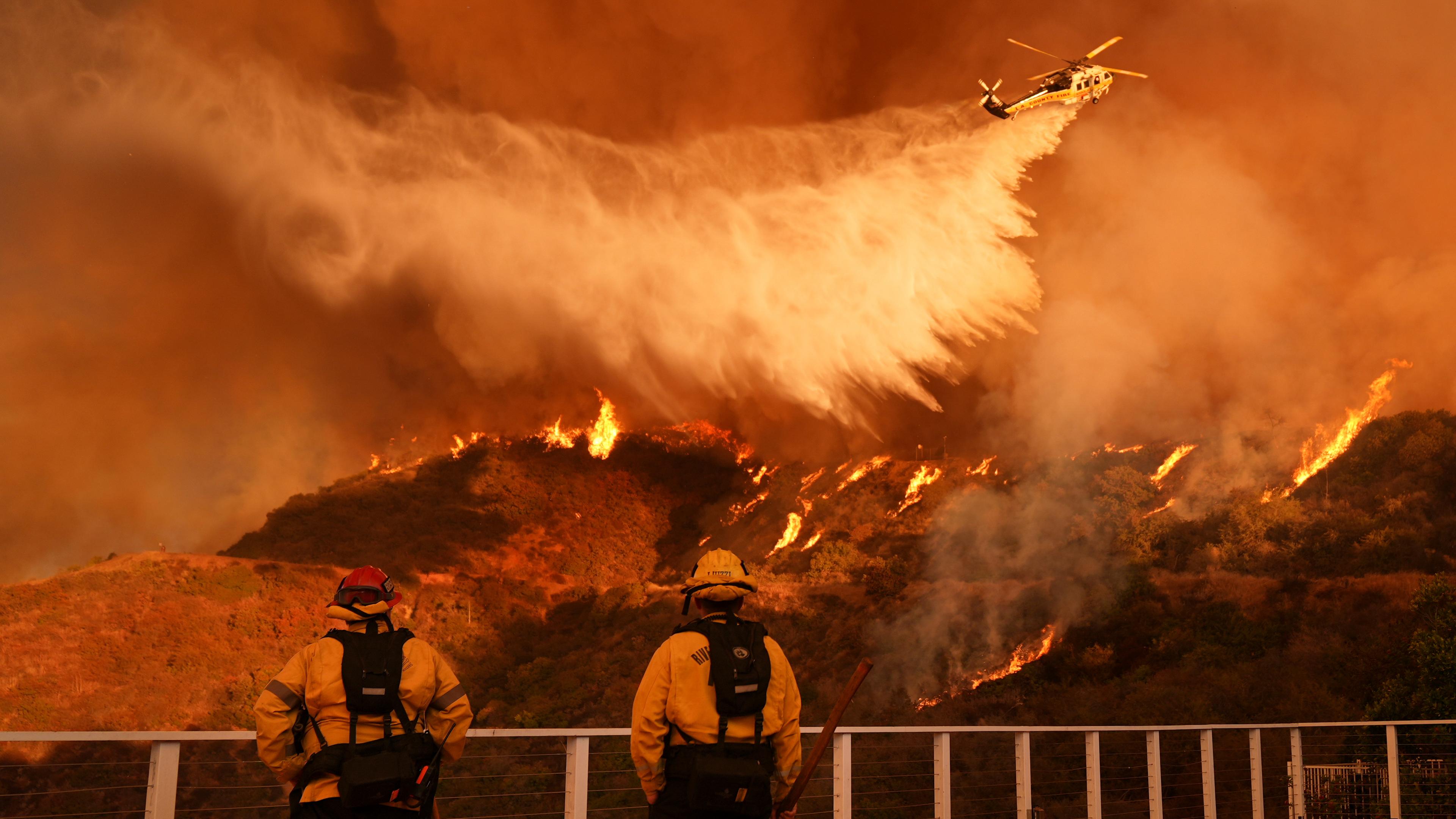 Feuerwehrleute beobachten, wie Löschwasser auf das Palisades-Feuer im Mandeville Canyon Angeles geworfen wird. 