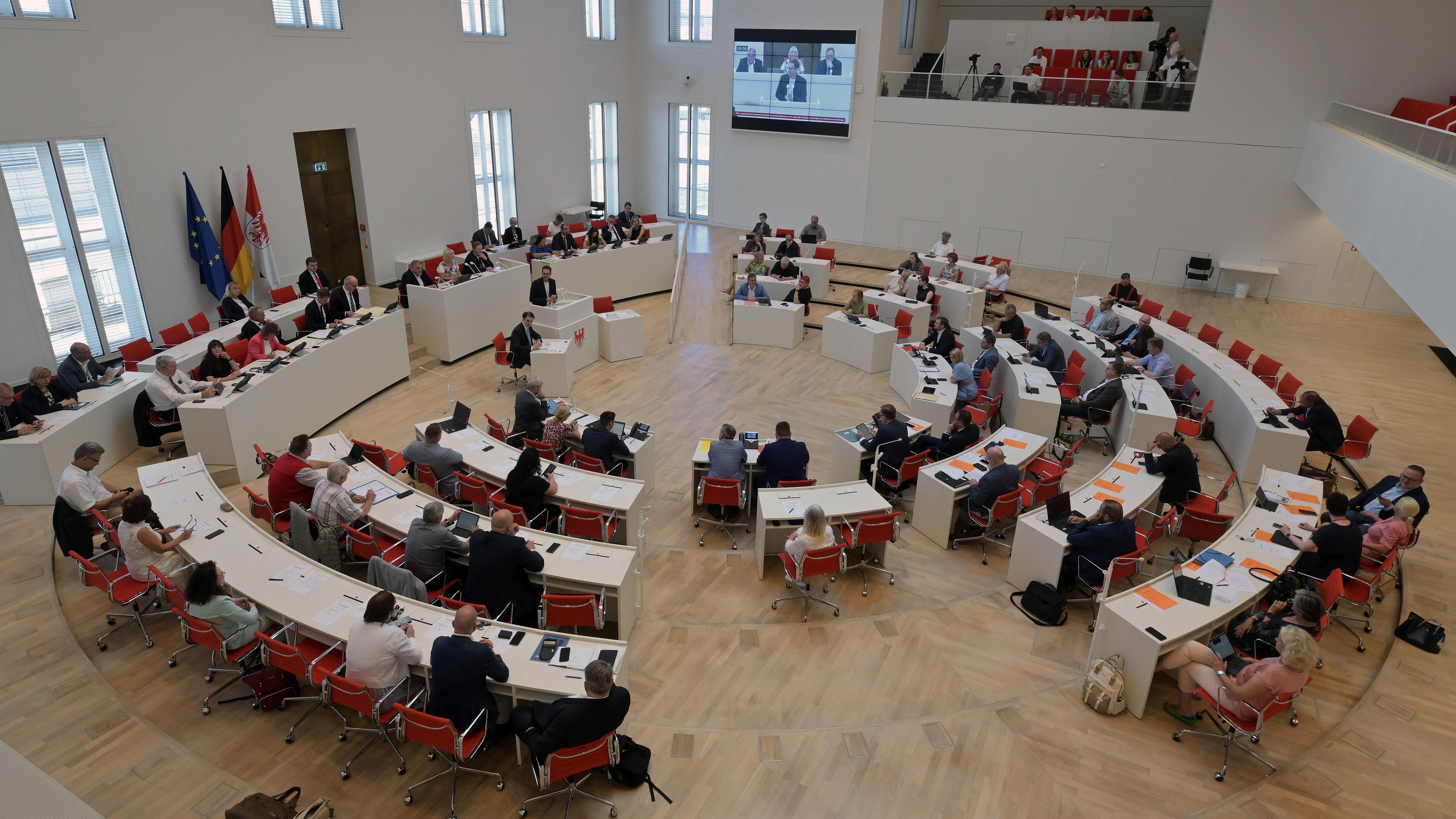 Der Brandenburger Landtag von innen. Die Sitze sind in einem Kreis aufgebaut. Die Blickrichtung ist in die Mitte.