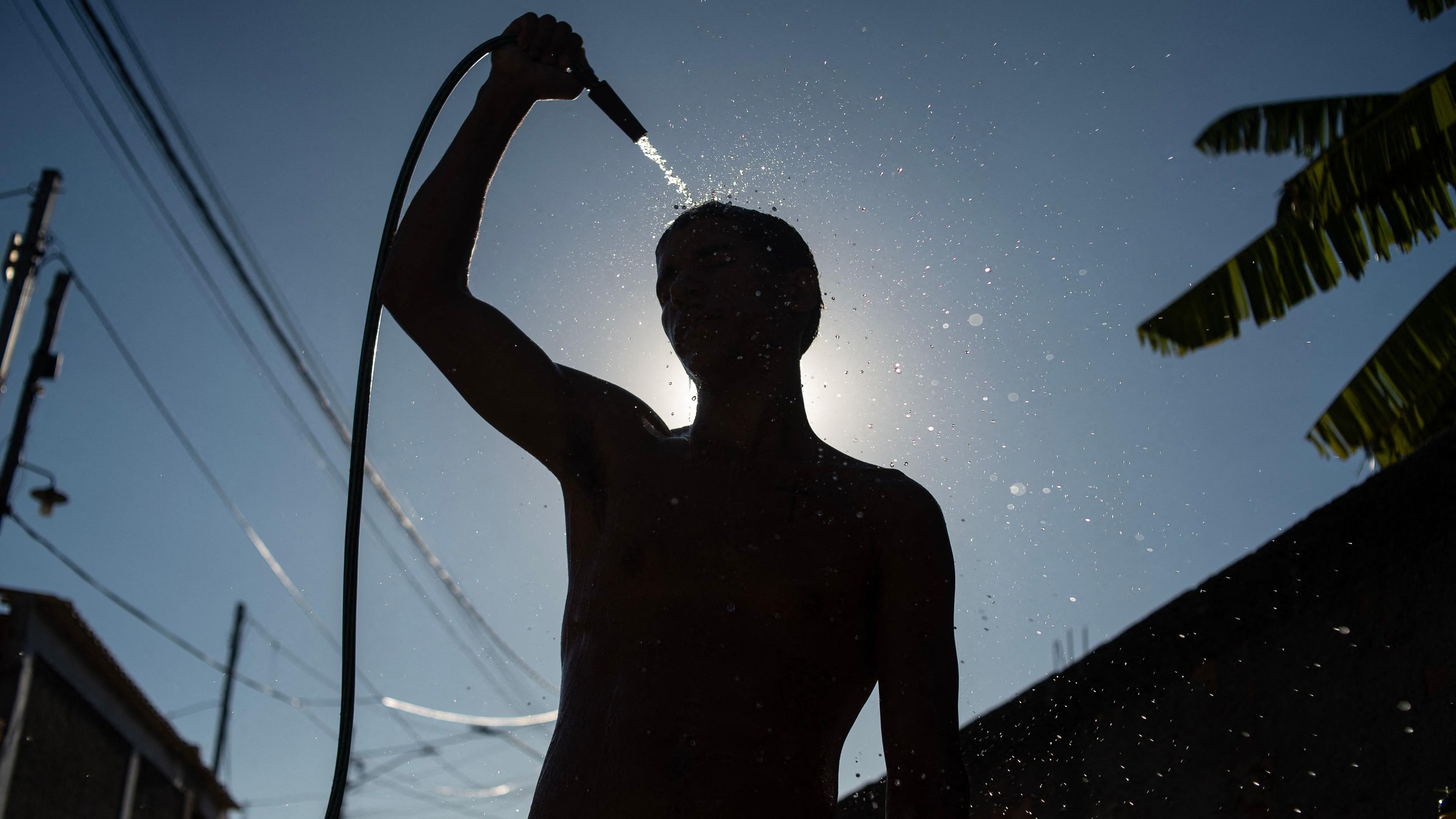 Ein Mann erfrischt sich mit einem Wasserschlauch während einer Hitzewelle in der brasilianischen Stadt Rio de Janeiro.