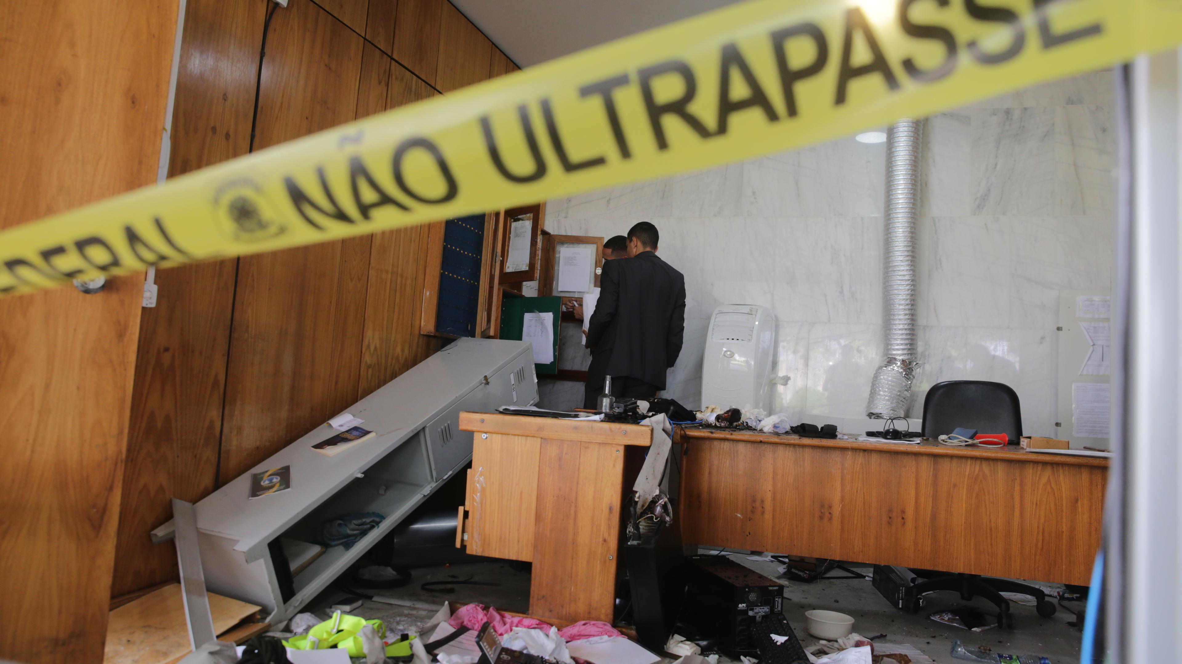Brasilien, Planalto Palace: Zwei Männer untersuchen ein zerstörtes Büro.