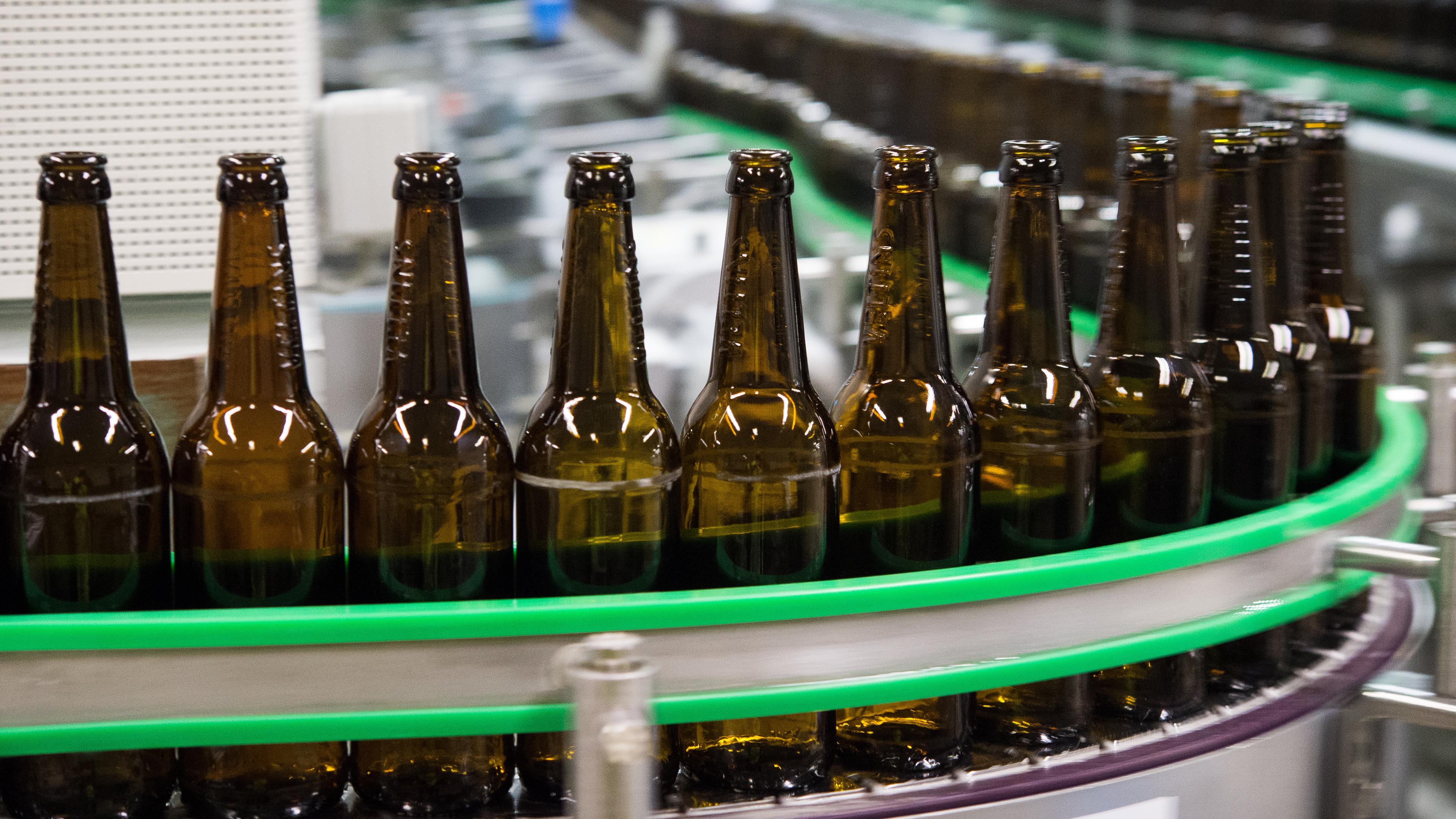 Leere Bierflaschen auf einem Fließband in einer Brauerei.