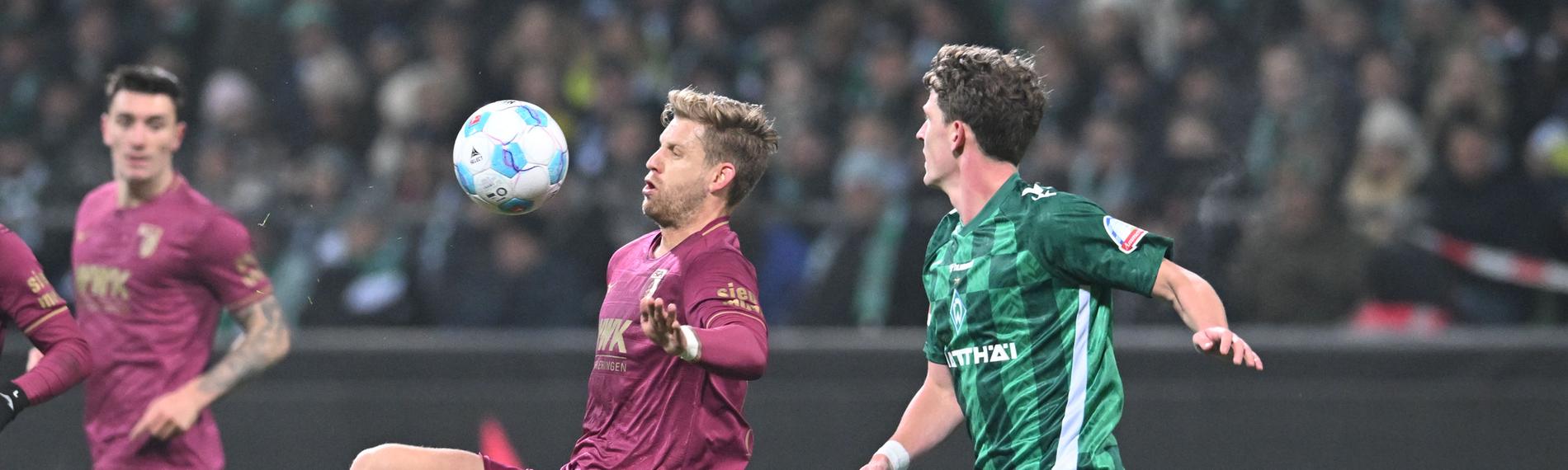 Werders Jens Stage (l) kämpft gegen Augsburgs Arne Maier um den Ball.