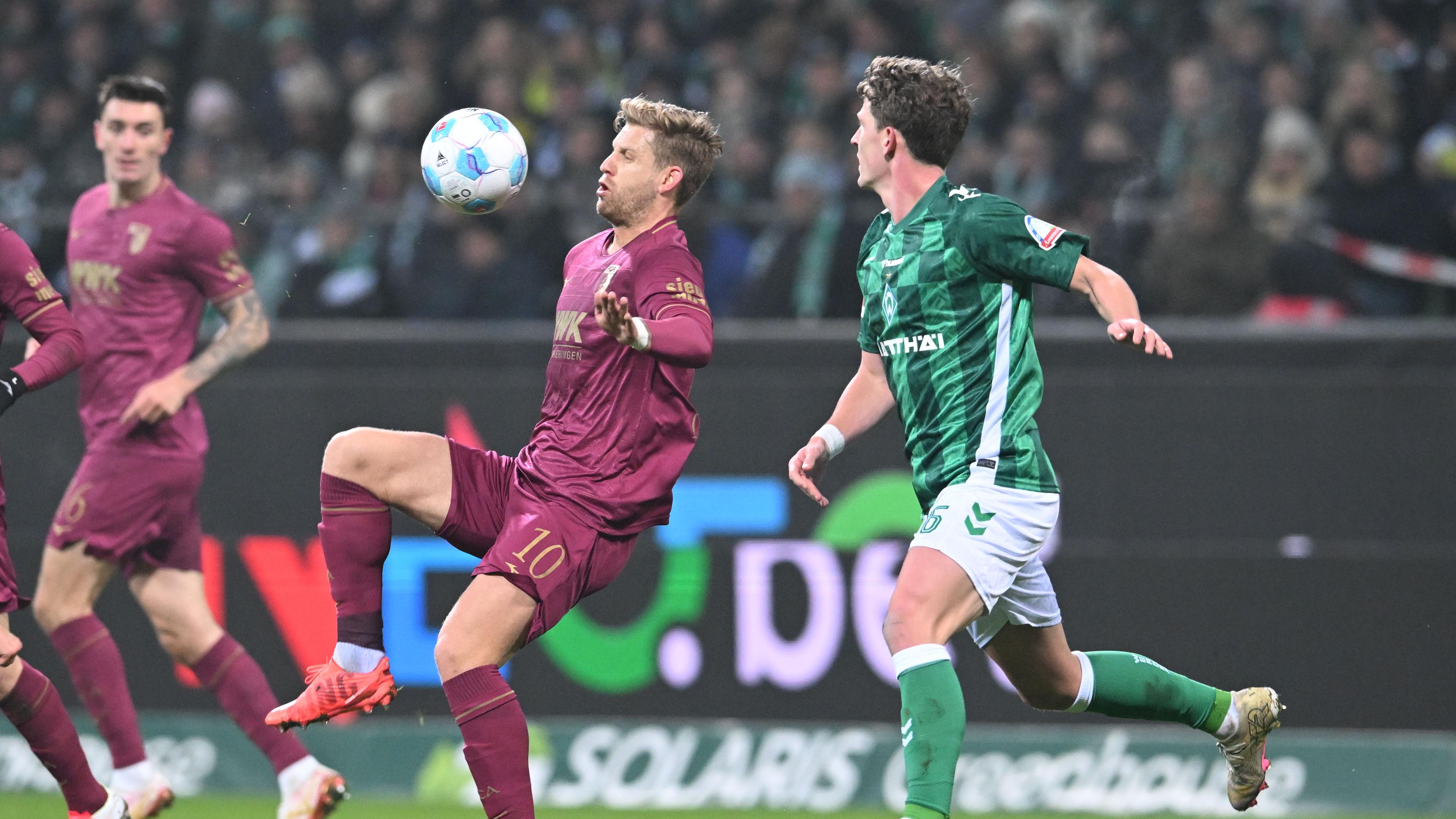 Werders Jens Stage (l) kämpft gegen Augsburgs Arne Maier um den Ball.