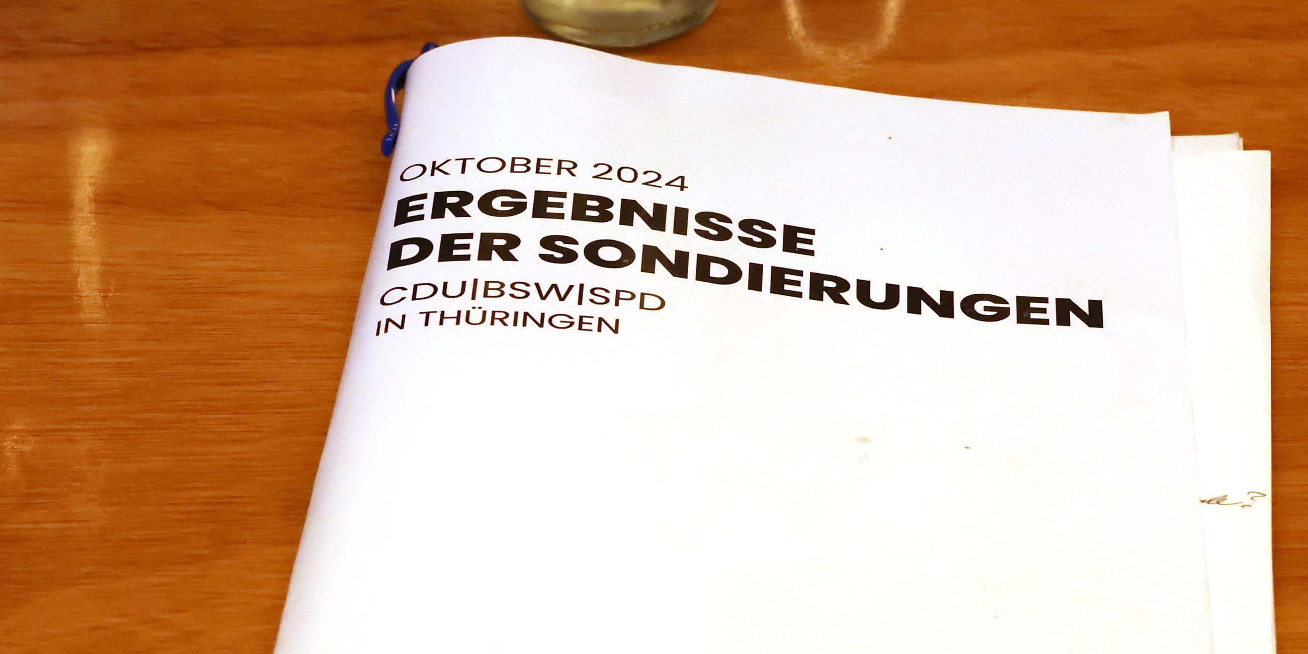  Eine Mappe mit der Aufschrift "Ergebnisse der Sondierungen" liegt auf einem Tisch bei dem Mitgliedertreffen des BSW-Landesverband im Tagungsraum.