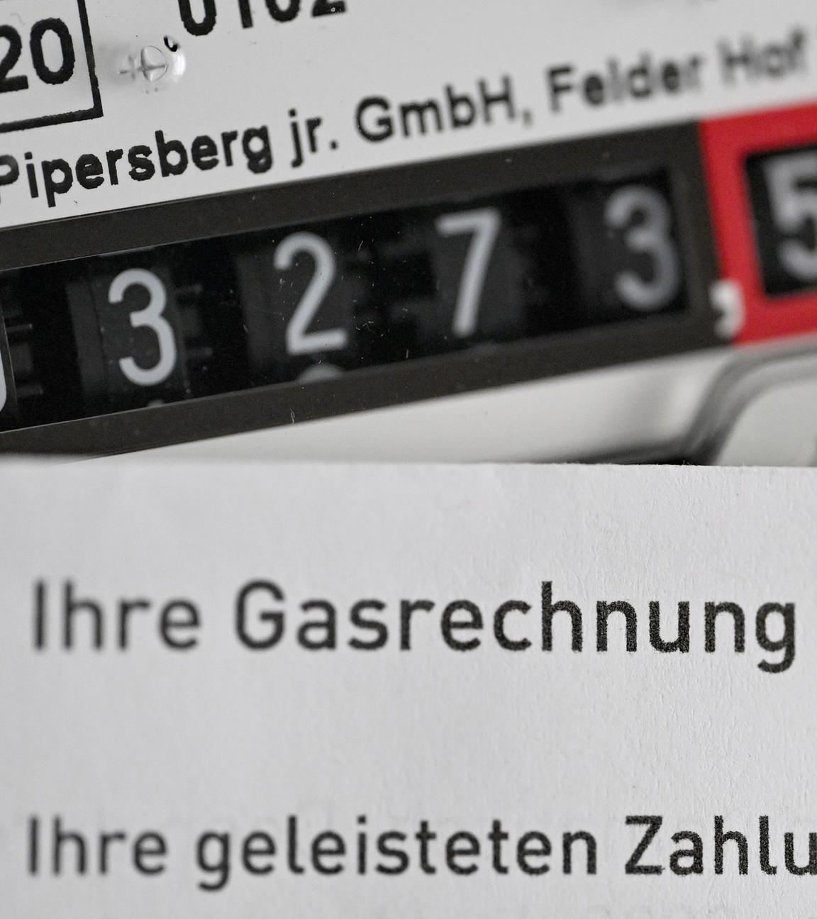 Eine Gasrechnung wird vor einen Gaszähler in einem privaten Haushalt gehalten