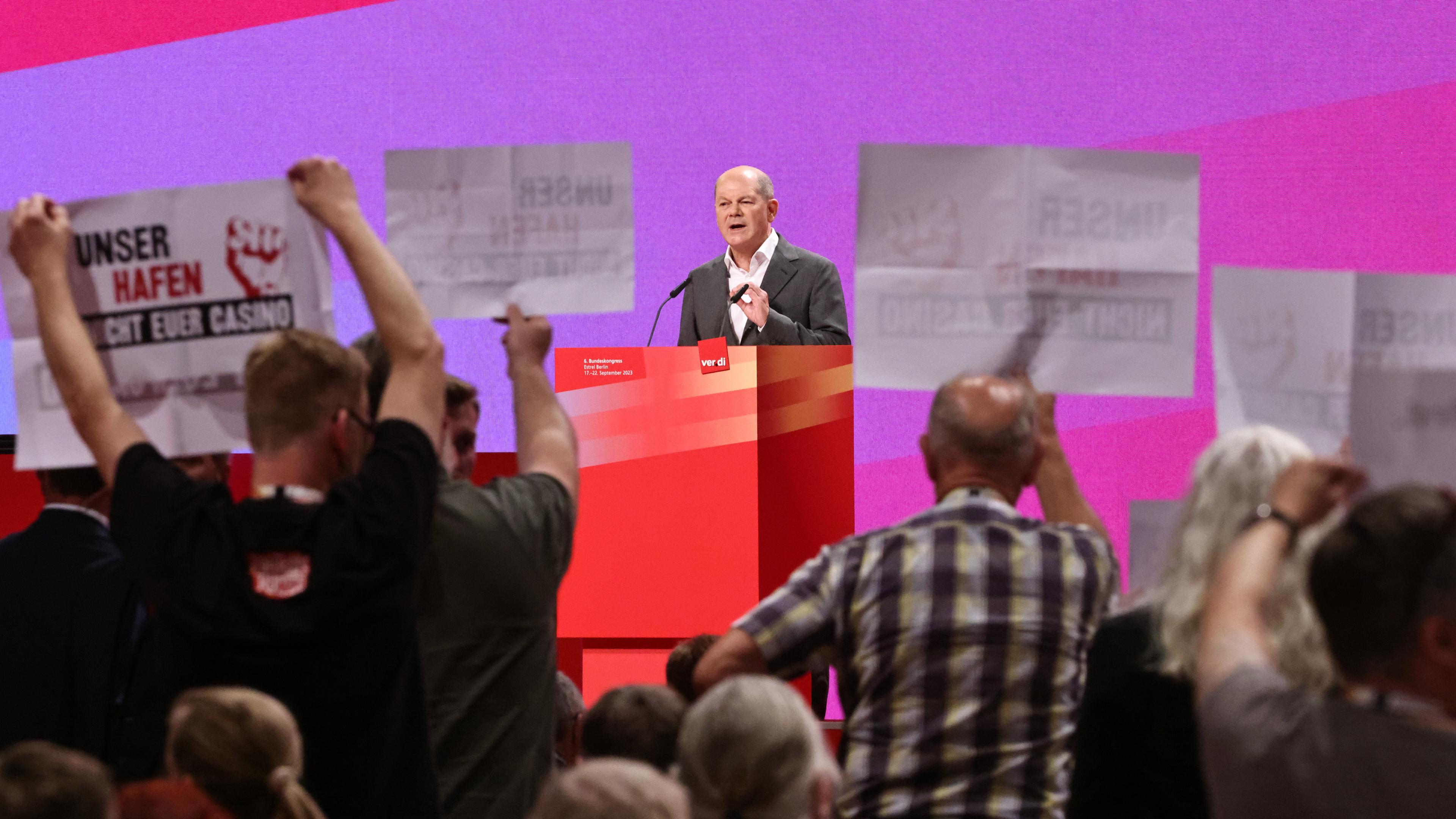 Scholz während seiner Rede auf dem Verdi-Bundeskongress. Vor ihm Protestschilder der Delegierten.