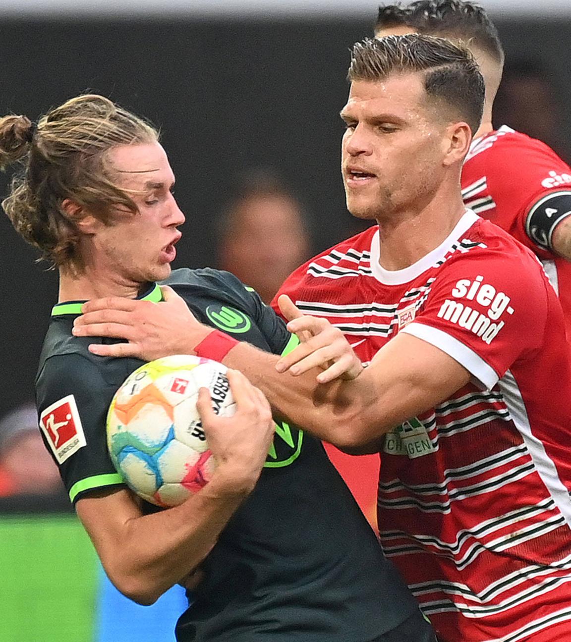 08.10.2022, Augsburg: Florian Niederlechner (FC Augsburg) packt Patrick Wimmer (Wolfsburg) an der Gurgel