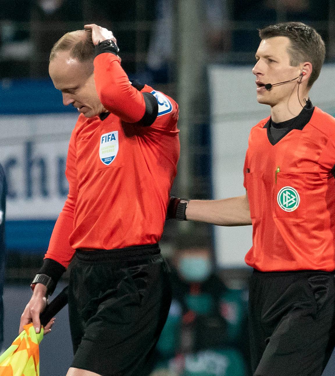 Das Schiedsrichtergespann um Benjamin Cortuns (r) verlässt während des Spiels das Spielfeld, nachdem Schiedsrichterassistent Christian Gittelmann (2.v.r.) einen Becher an den Kopf bekommen hatte.