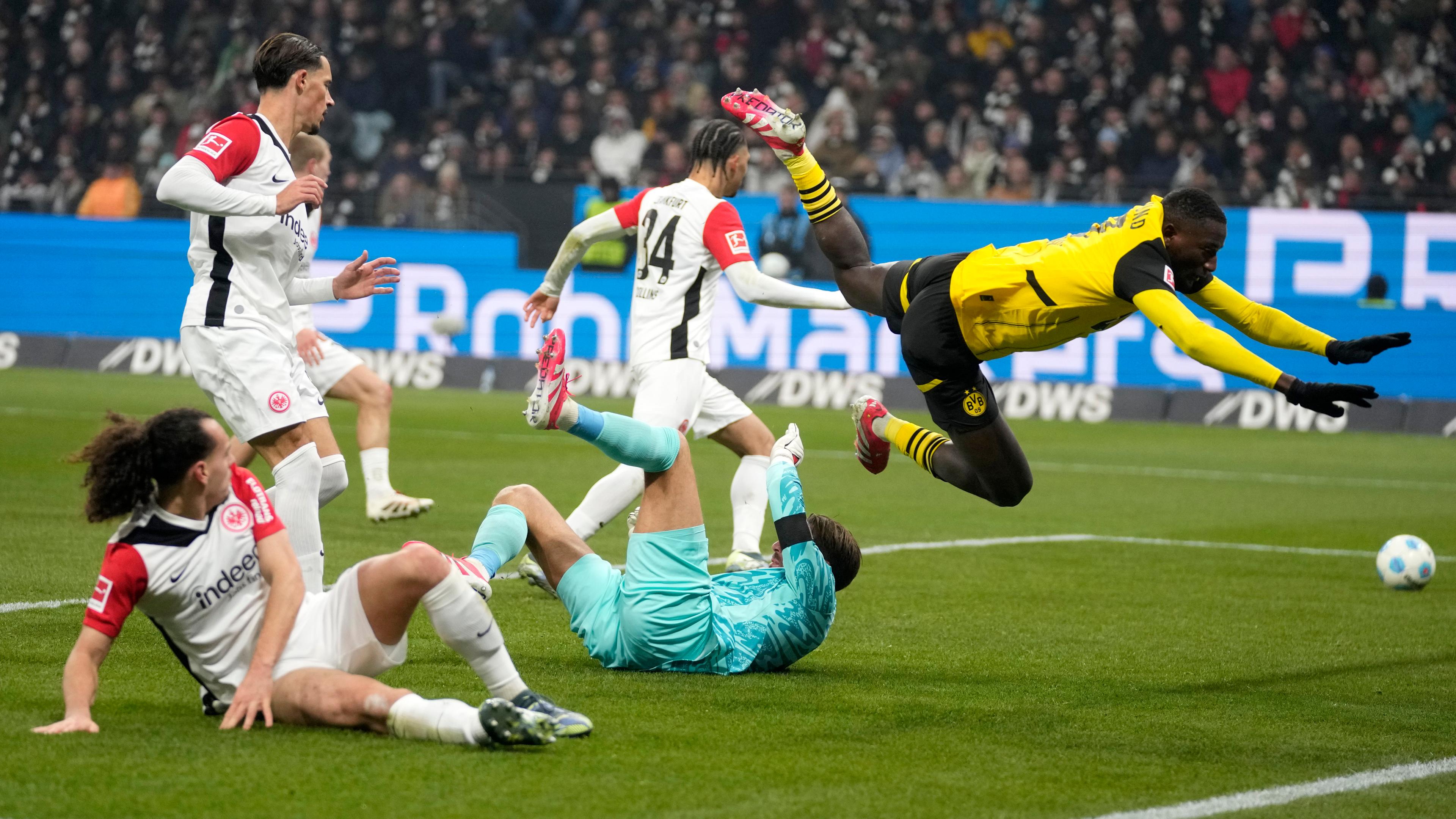 Dortmunds Serhou Guirassy fällt über Frankfurts Torwart Kevin Trapp.