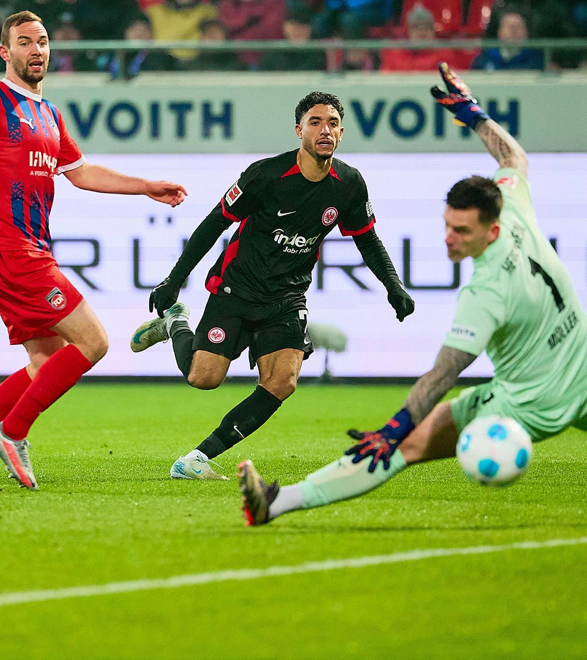 Omar Marmoush von der Eintracht frankfurt schießt das Tor zum 3:0 gegen Torhüter Kevin Müller des 1. FC Heidenheim.