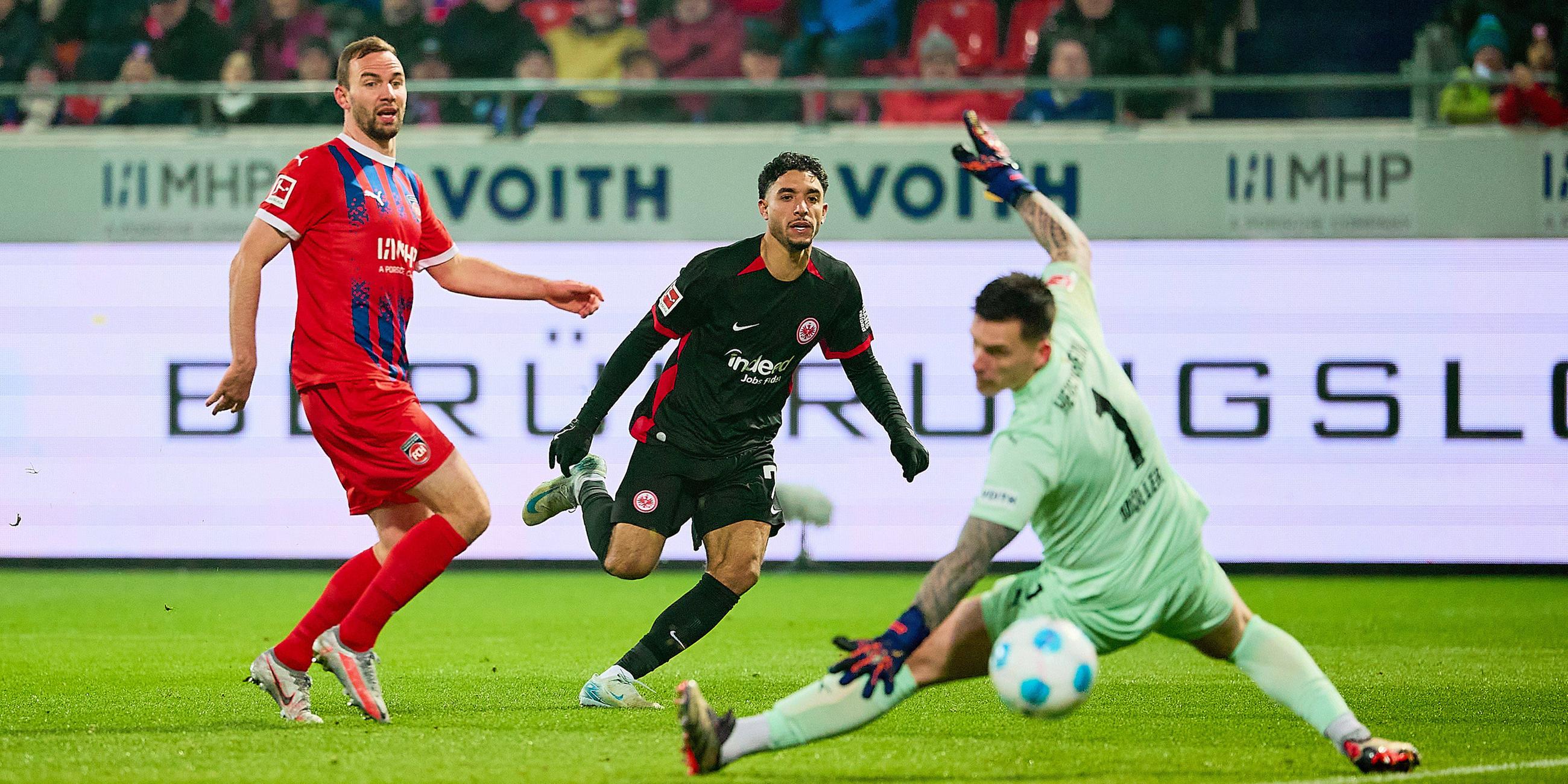 Omar Marmoush von der Eintracht frankfurt schießt das Tor zum 3:0 gegen Torhüter Kevin Müller des 1. FC Heidenheim.