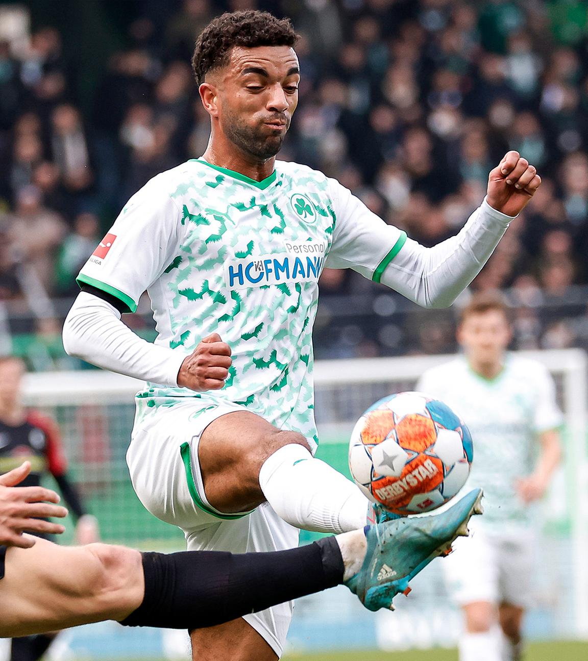 Der Fürther Timothy Tillman (r.) und der Freiburger Nico Schlotterbeck (l.) gehen mit gestreckten Beinen zum Ball.