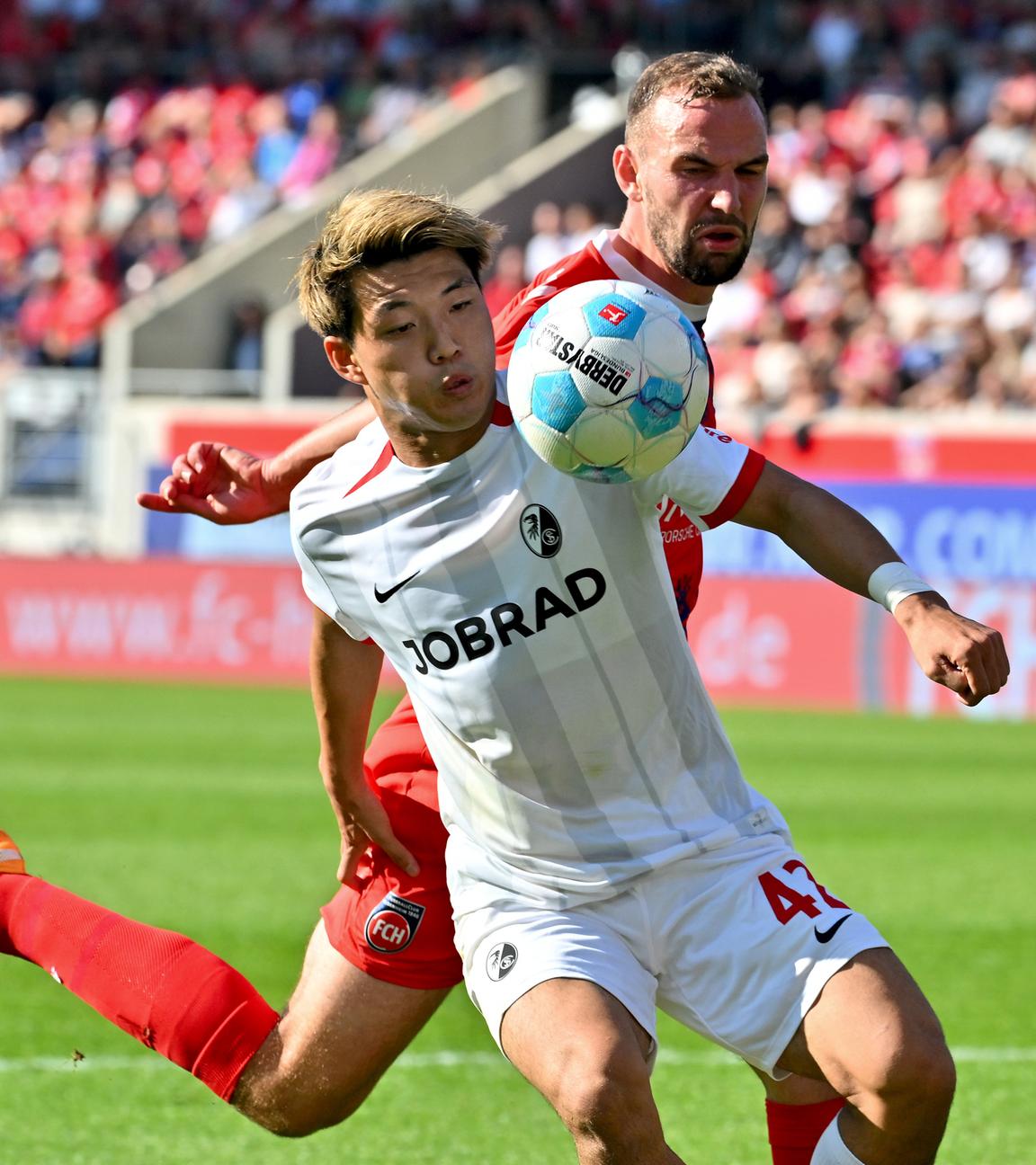 Ritsu Doan vom SC Freiburg im Zweikampf mit Heidenheims Benedikt Gimber.